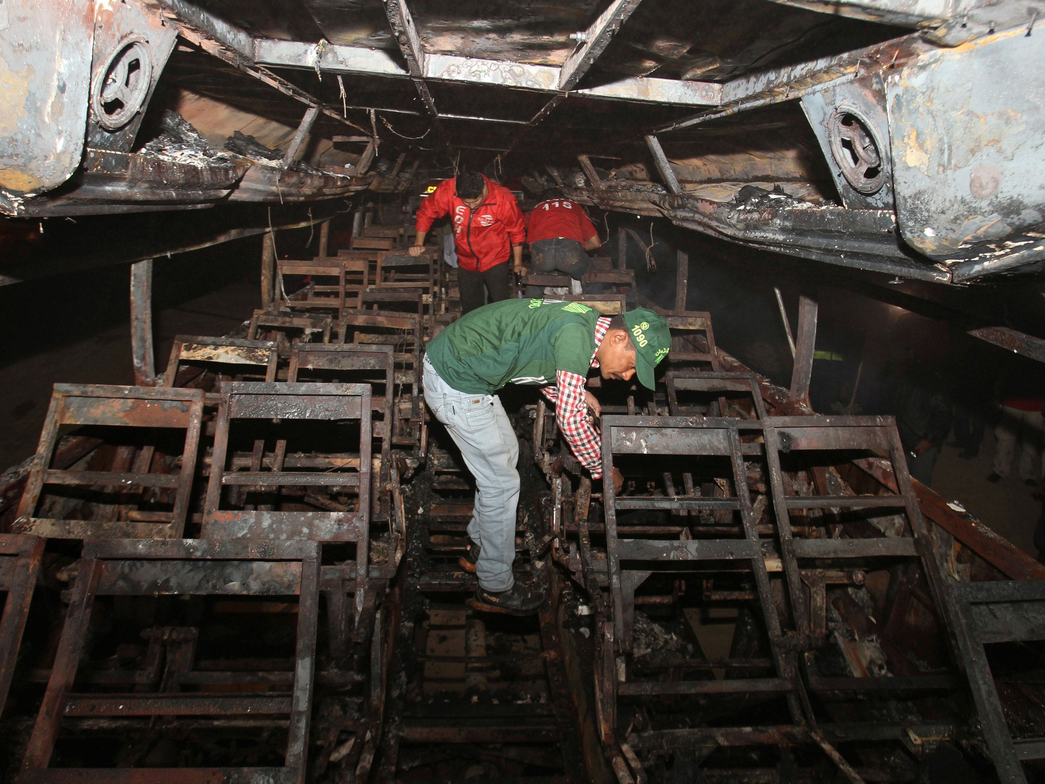 Pakistani rescue workers search through the wreckage of a passenger bus destroyed after colliding with an oil tanker on a highway near Karachi, Pakistan