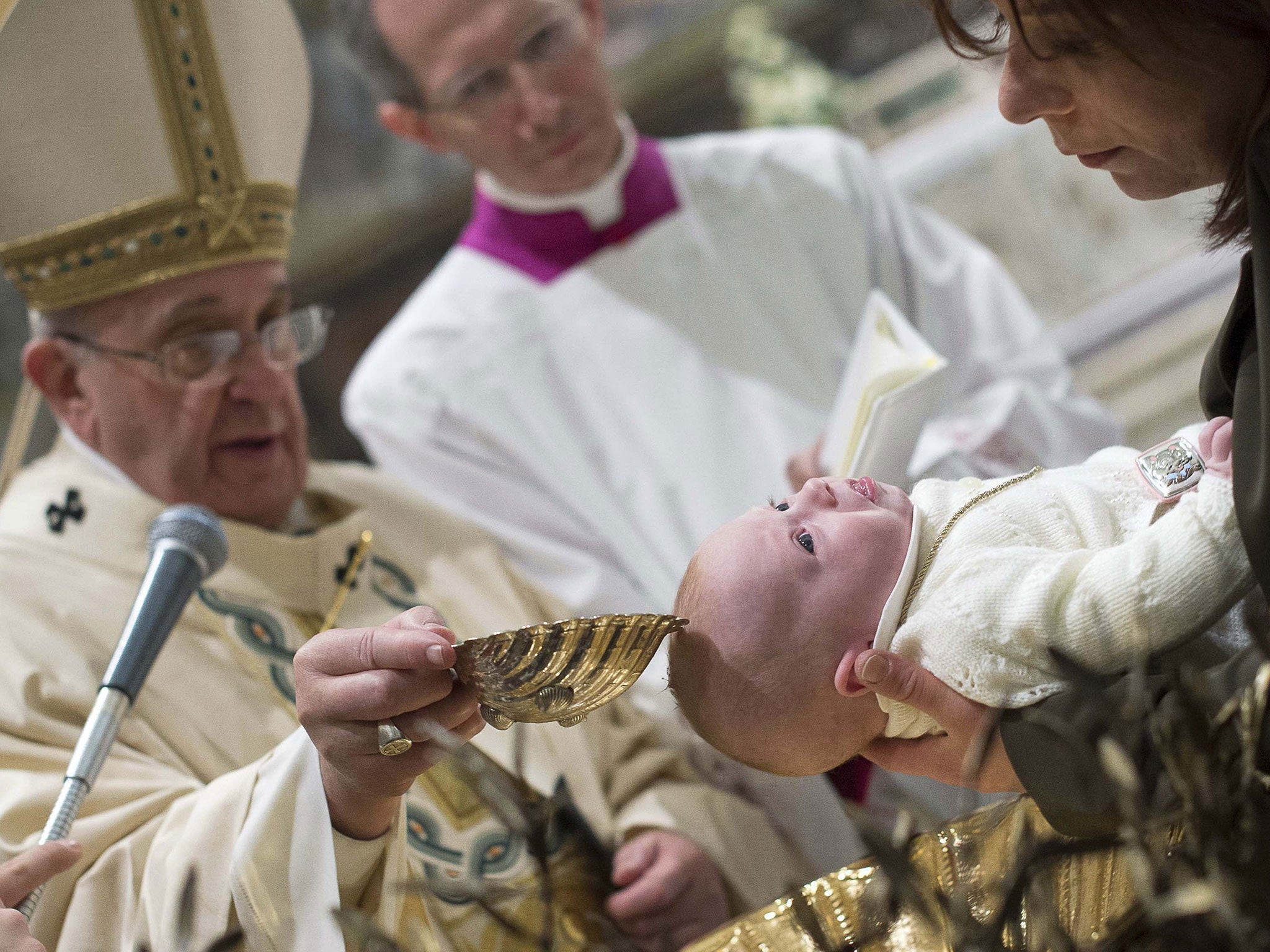 Pope Francis baptises a newborn during a solemn mass in the Sistine Chapel at the Vatican January 11, 2015