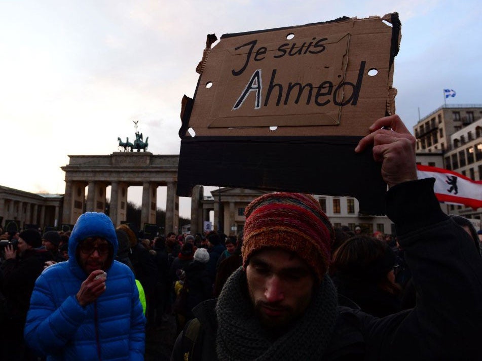 A person at a vigil in Berlin holds up a 'Je suis Ahmed' poster during a rally on Sunday 11 January 2015.