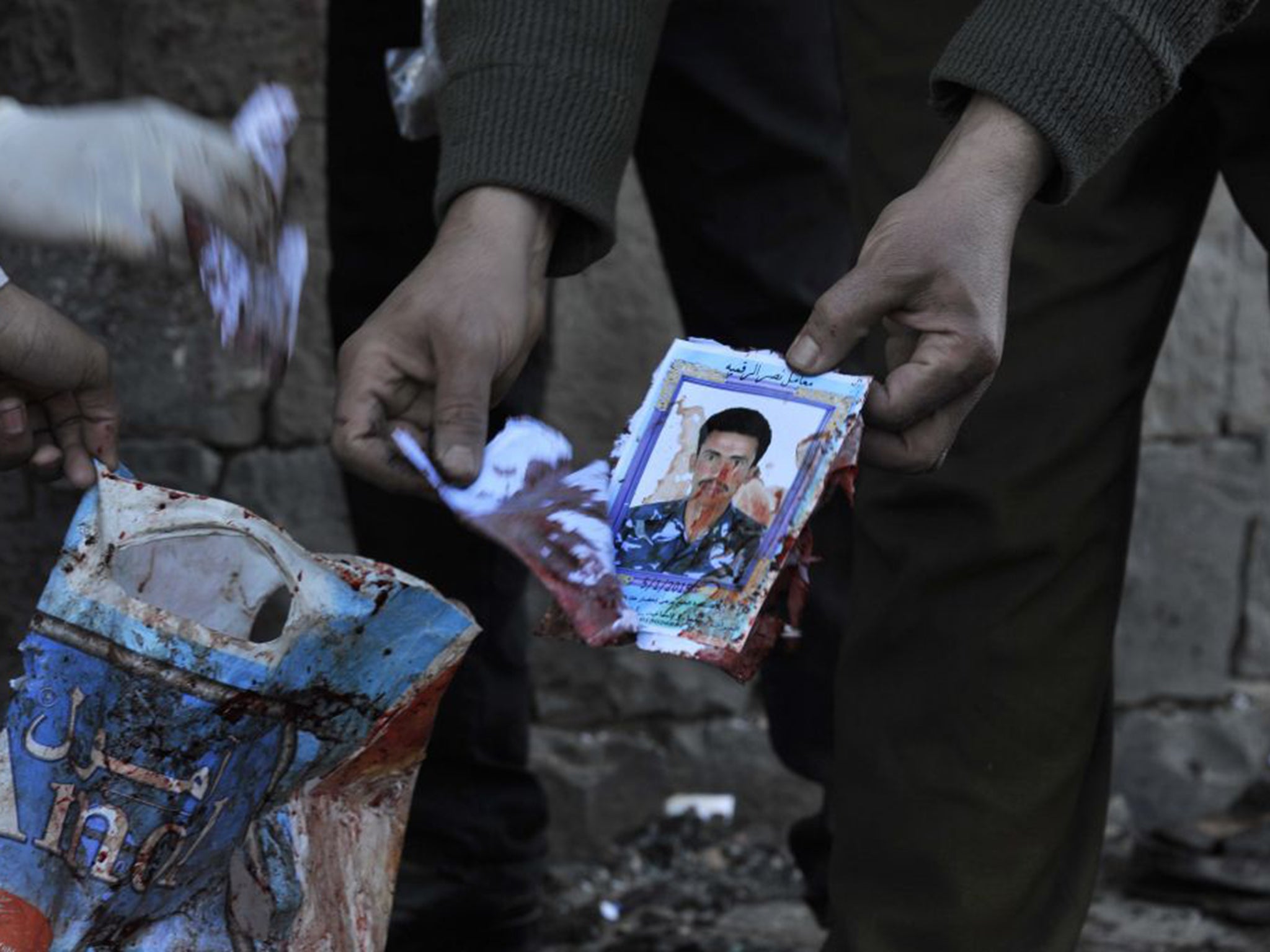 A Yemeni soldier holds the photo of a victim of a car bombing outside a police academy in Sanaa