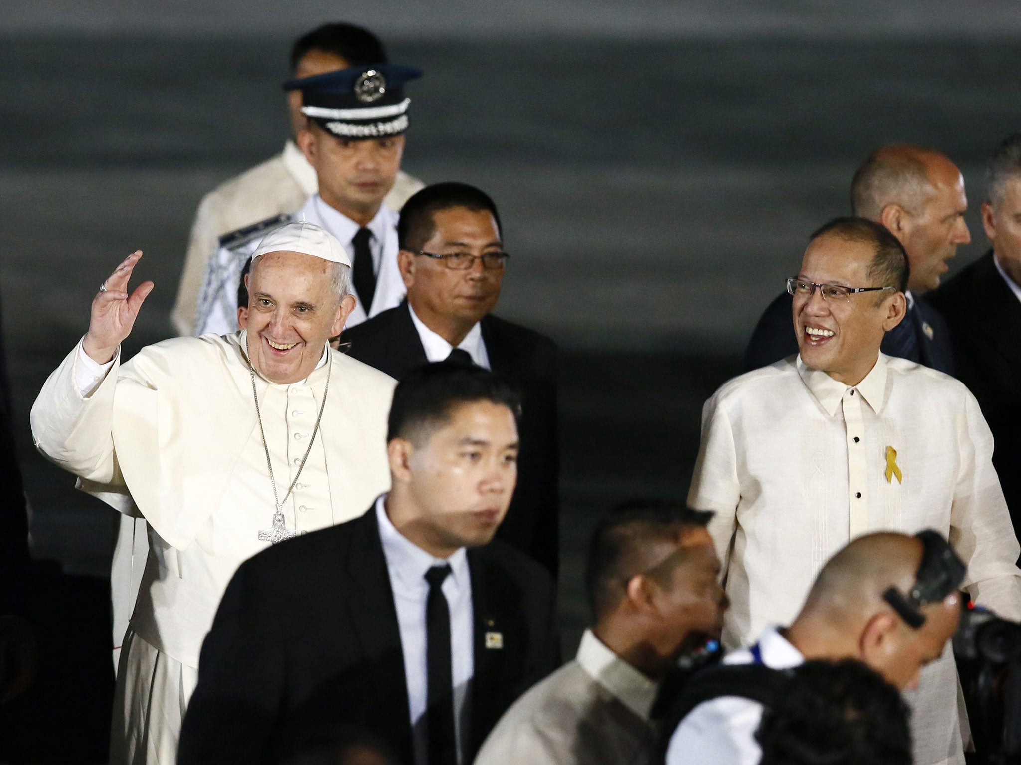 Pope Francis, new hat acquired, waves next to Philippine President Benigno Aquino III (R) during his arrival at the airport in Manila