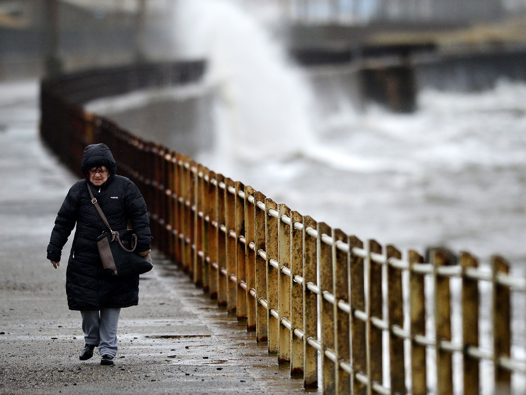 Strong waves begin to build as a woman walks along by the sea in Saltcoats, Scotland. (Getty)