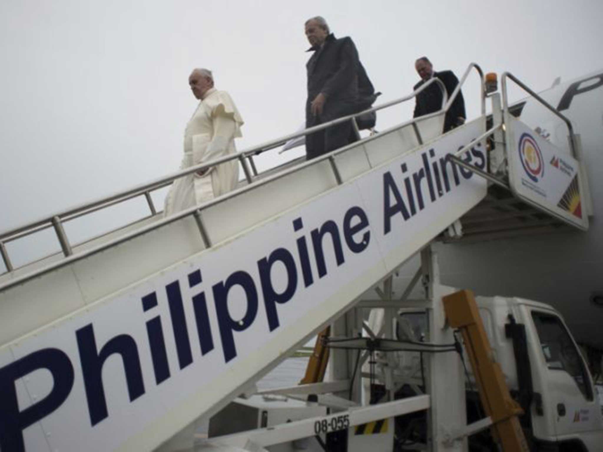 Pope Francis disembarks from a passenger jet with his aides upon his arrival at Tacloban airport