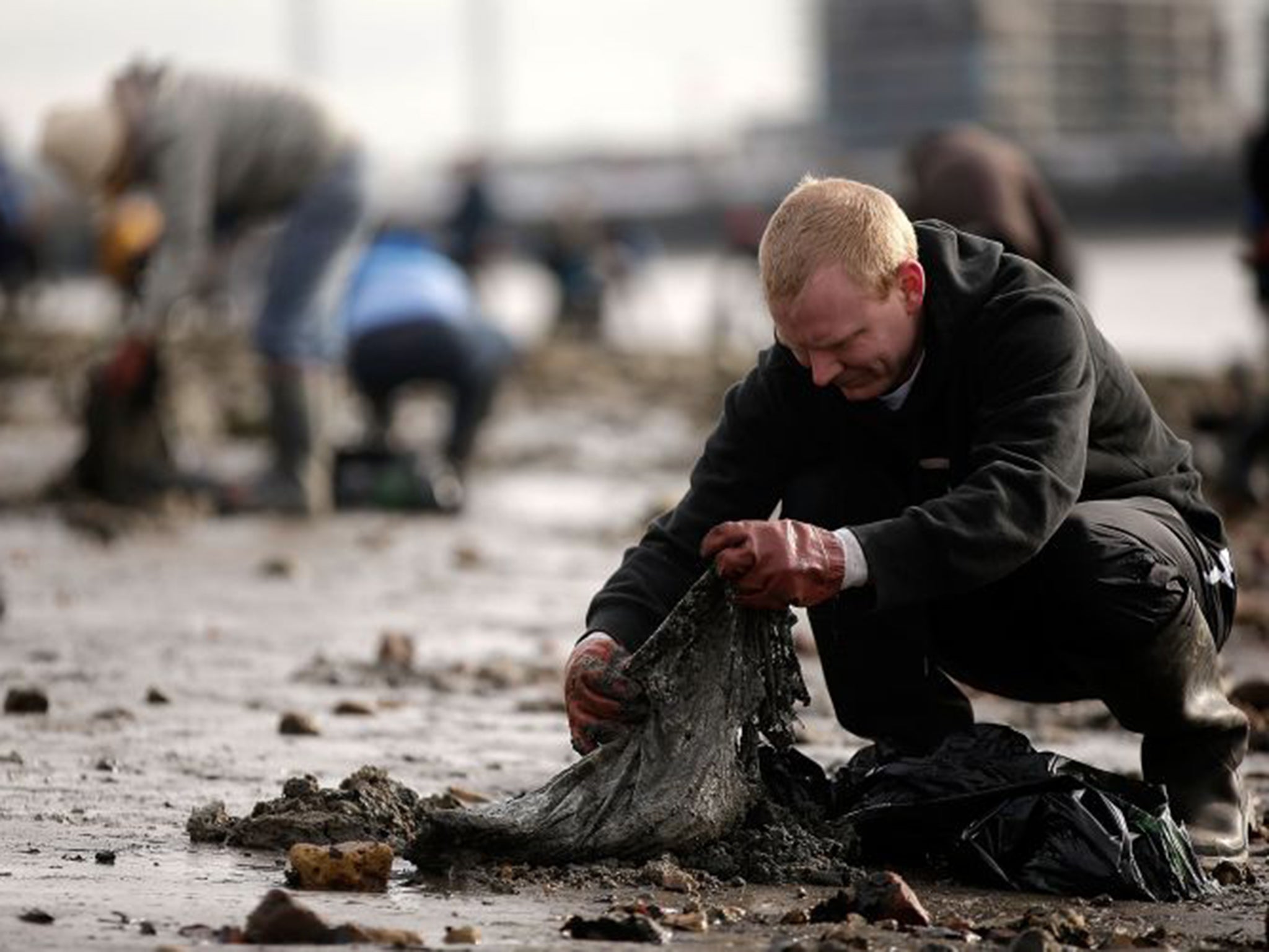 A volunteer cleans the banks of the River Thames of rubbish and debris on the Isle of Dogs