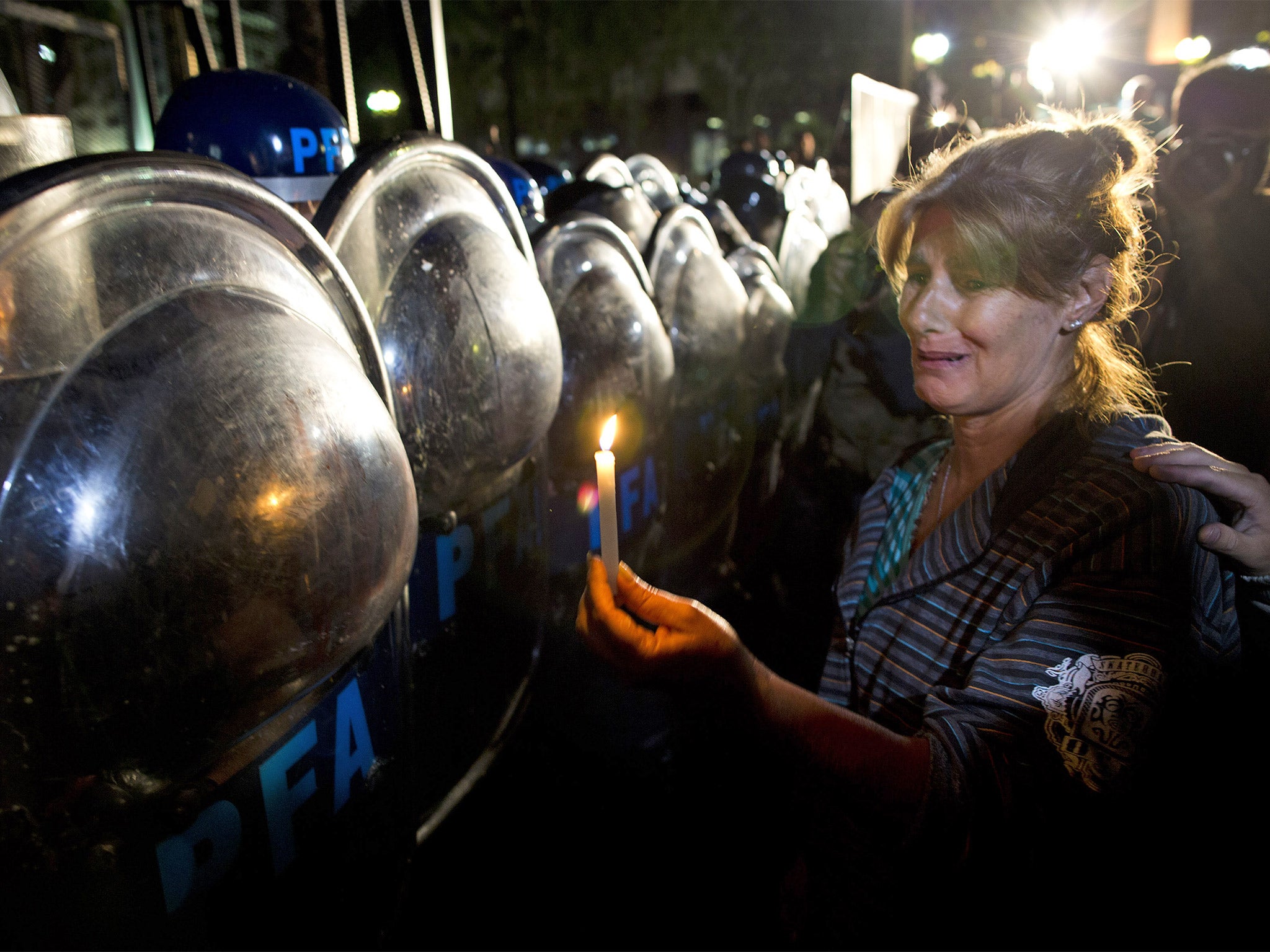 A protester holds a candle up to riot police during a vigil for Alberto Nisman, in Plaza de Mayo in Buenos Aires