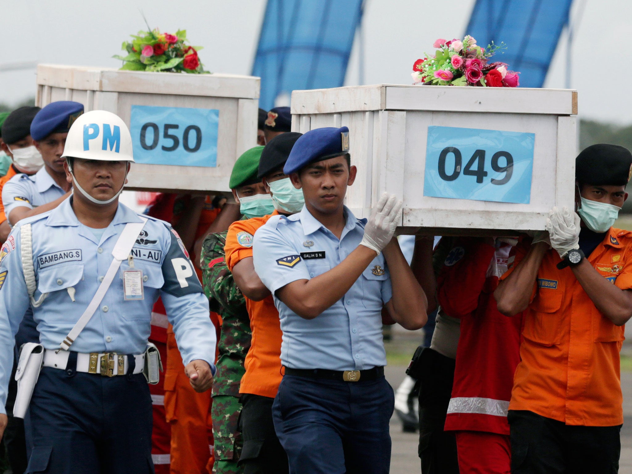 Members of the National Search and Rescue Agency carry coffins containing bodies of the victims aboard AirAsia Flight 8501 to transfer to Surabaya at the airport in Pangkalan Bun