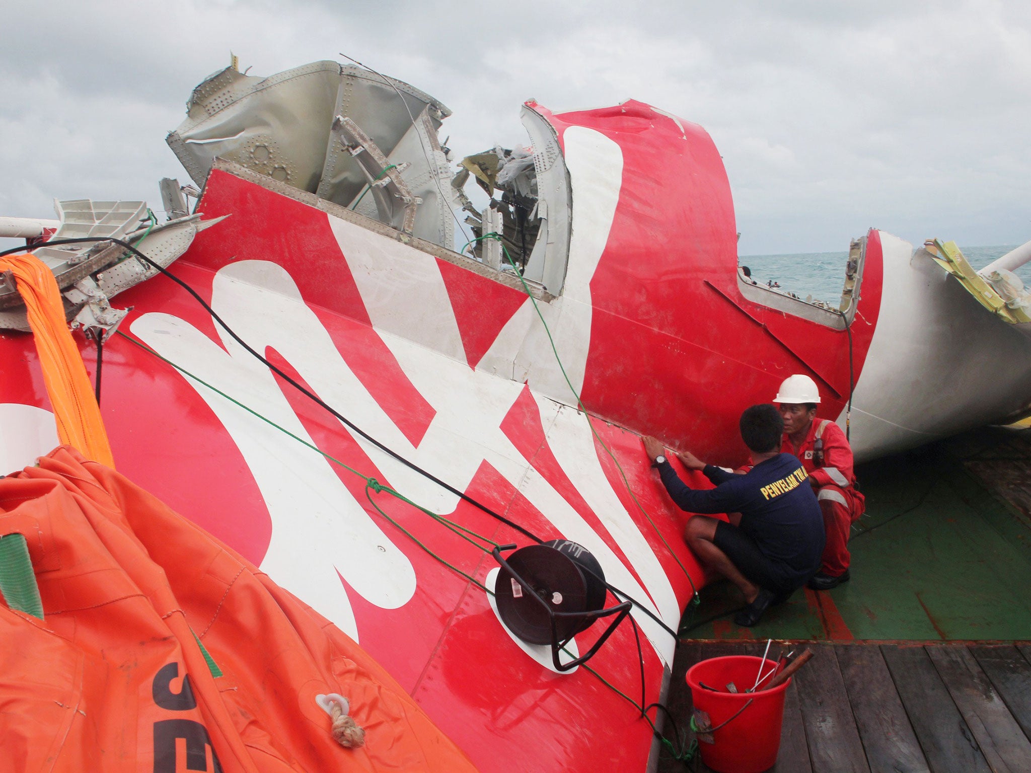 An Indonesian diver and an official examine the wreckage from AirAsia flight QZ8501