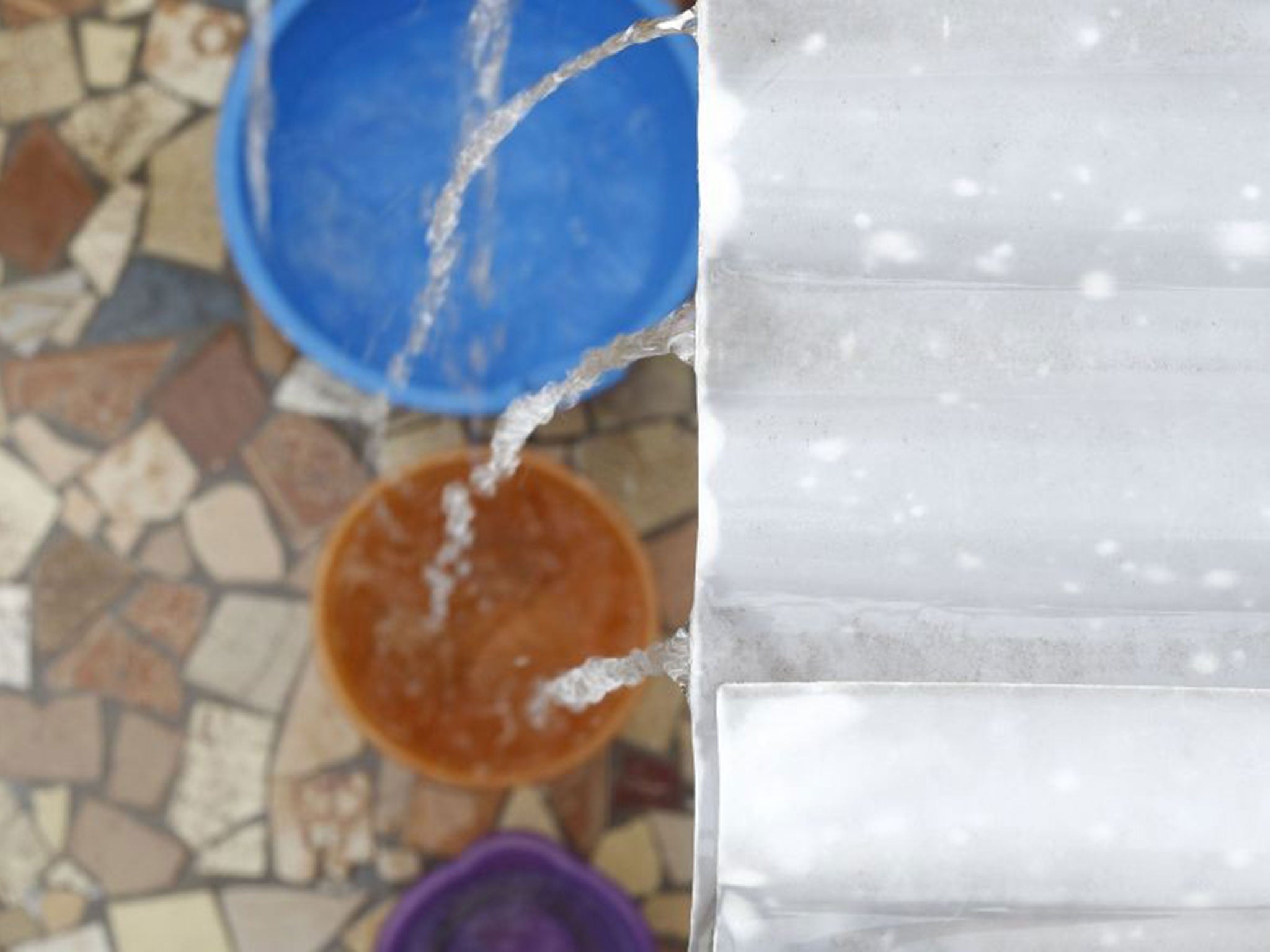 Residents of Sao Paulo collect rainwater falling from a roof, due to the lack of water in this Brazilian city, on January 22, 2015