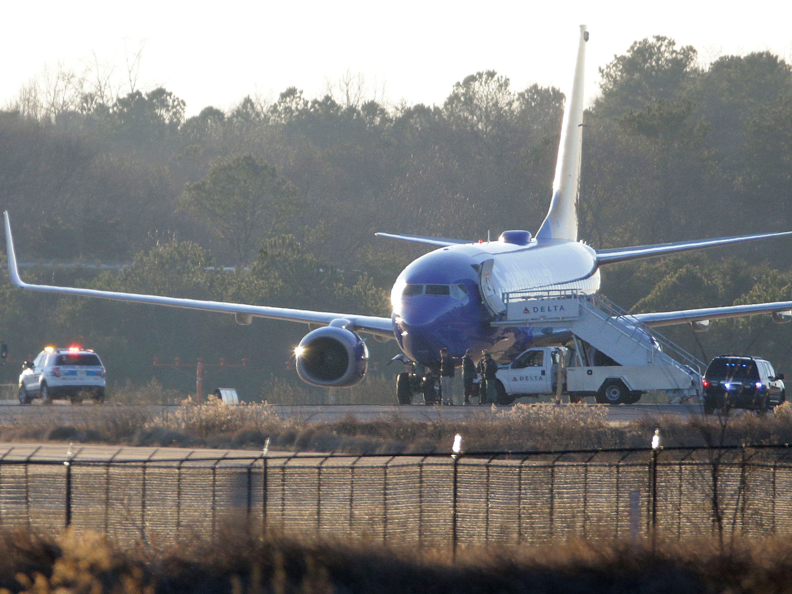 Law enforcement officials stand beneath a Southwest Airlines airplane as a bomb squad vehicle stands by at left on the tarmac at Hartsfield-Jackson Atlanta International Airport