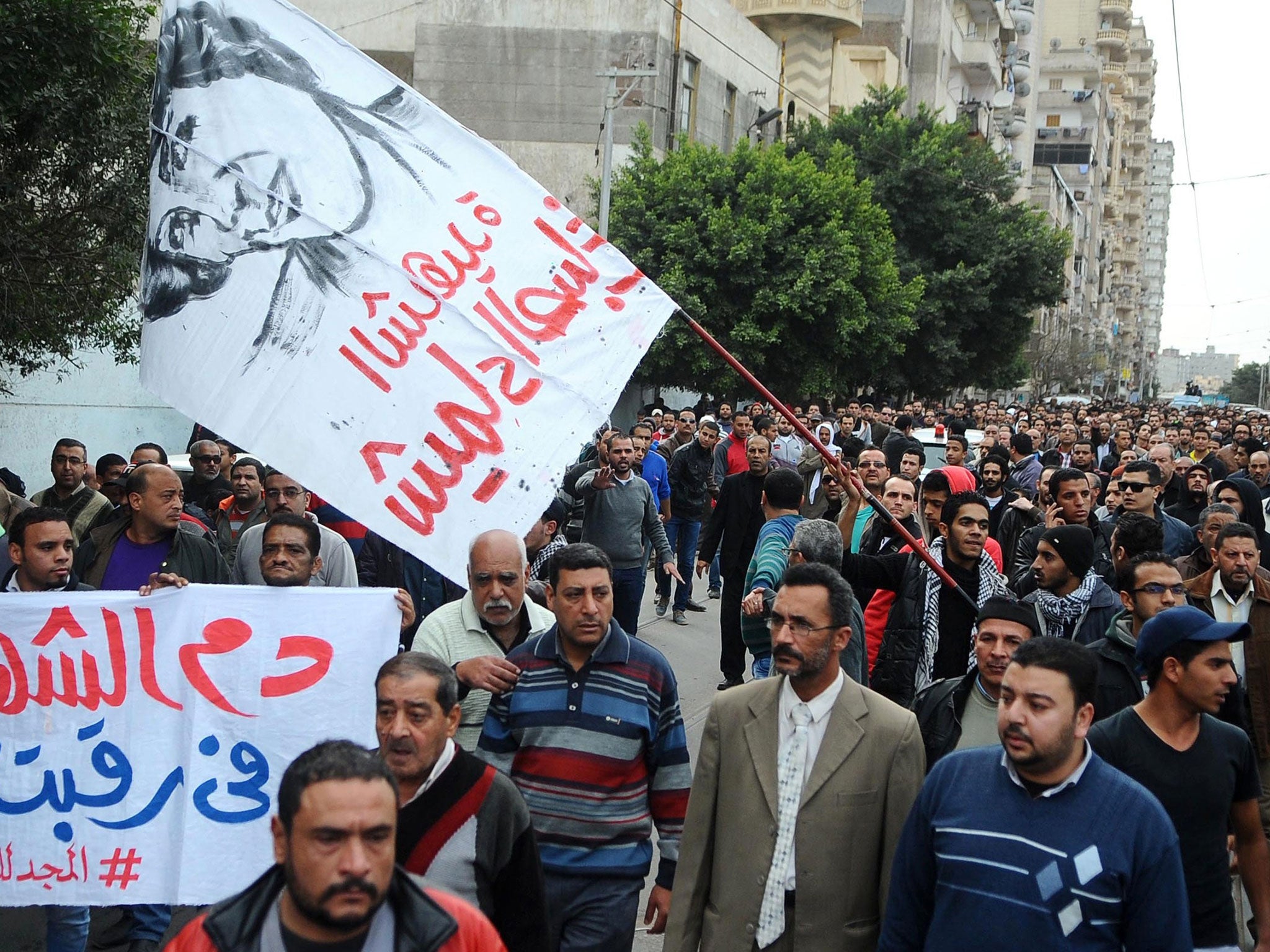 Egyptians hold banners during the funeral procession of Shaima al-Sabbagh, who was killed by police, on 25 January, 2015 (AFP)