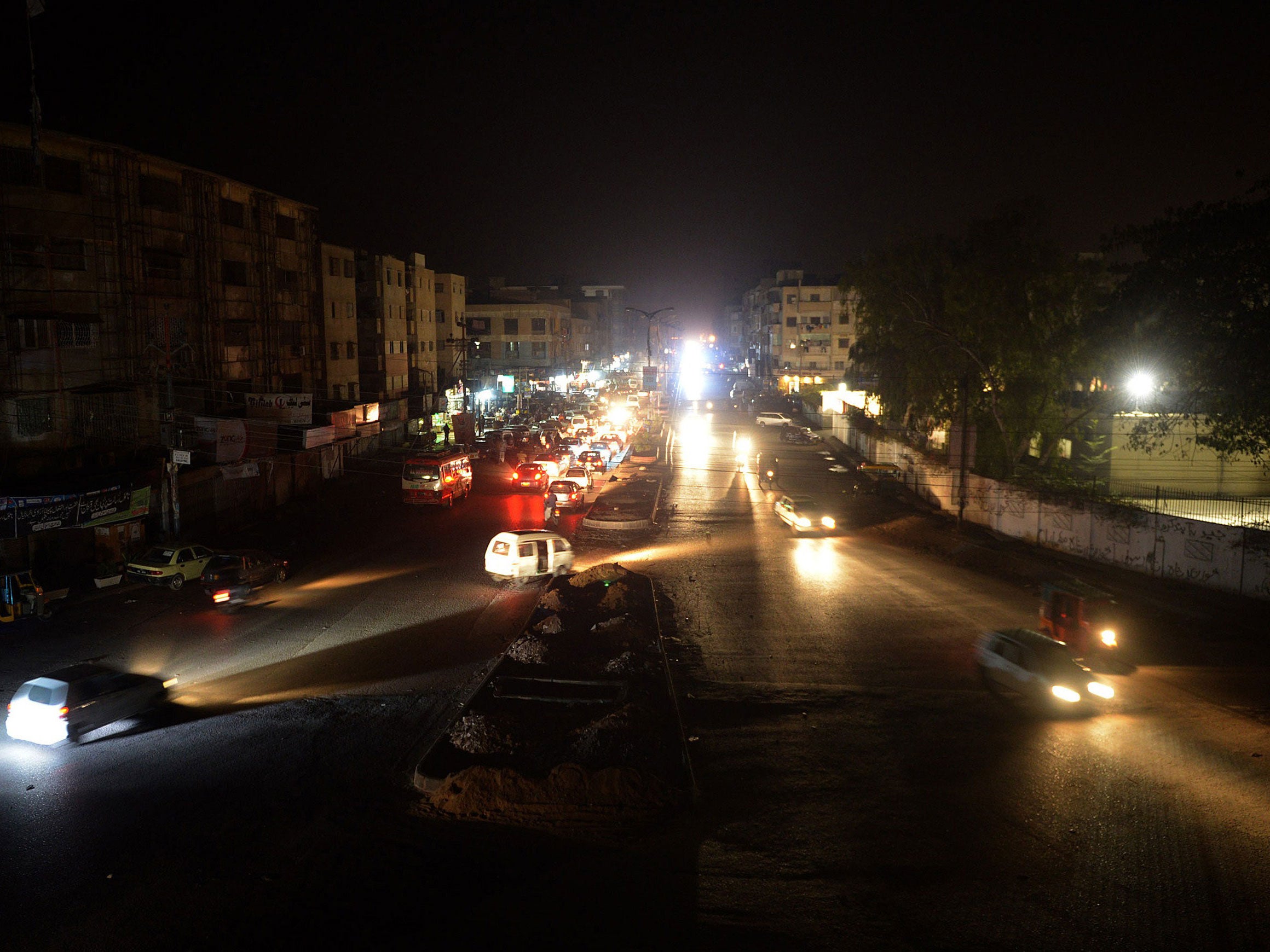 Pakistani motorists drive on an unlit street during a power cut in Karachi