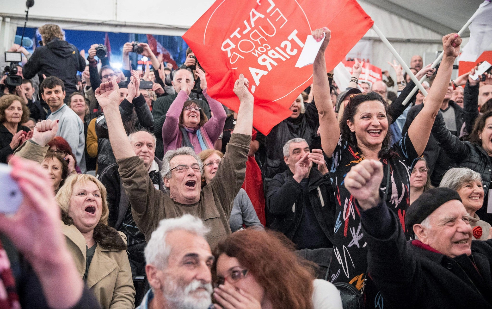 Supporters of the radical opposition party Syriza celebrate after the initial exit poll results for Greece's general elections are revealed