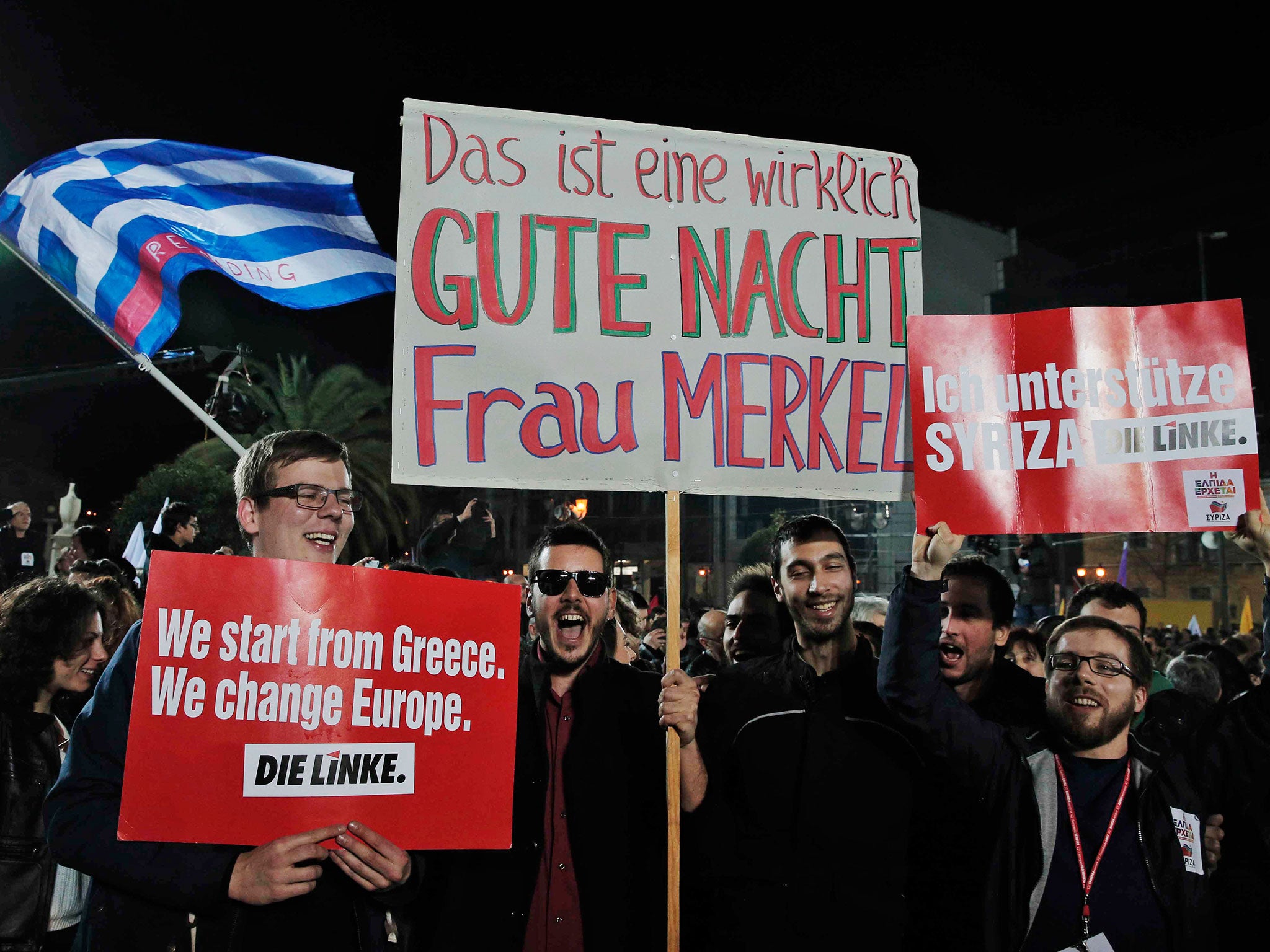 Supporters of Germany's left-wing Die Linke party, hold placards as they show their support to Alexis Tsipras, leader of Syriza left-wing party after his speech to supporters in central Athens