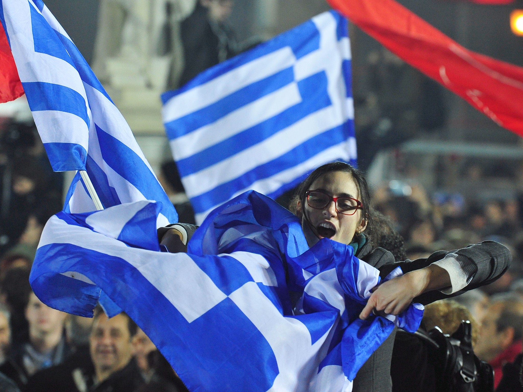 A woman waves a Greek flag during a speech by the leader of Syriza left-wing party Alexis Tsipras outside Athens University Headquarters