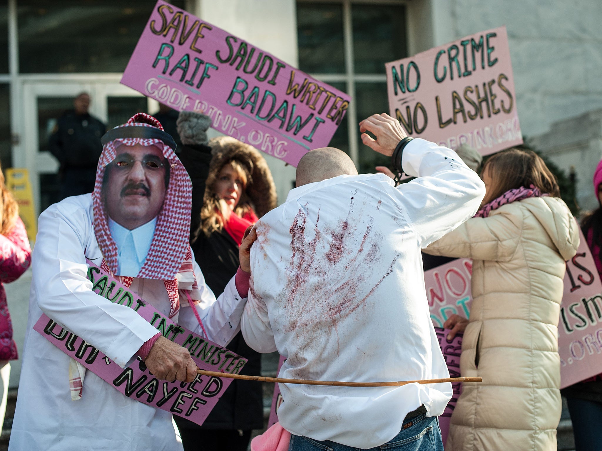 Protesters simulate a flogging in front of the Saudi embassy in Washington DC in protest against the 10-year prison sentence given to a blogger