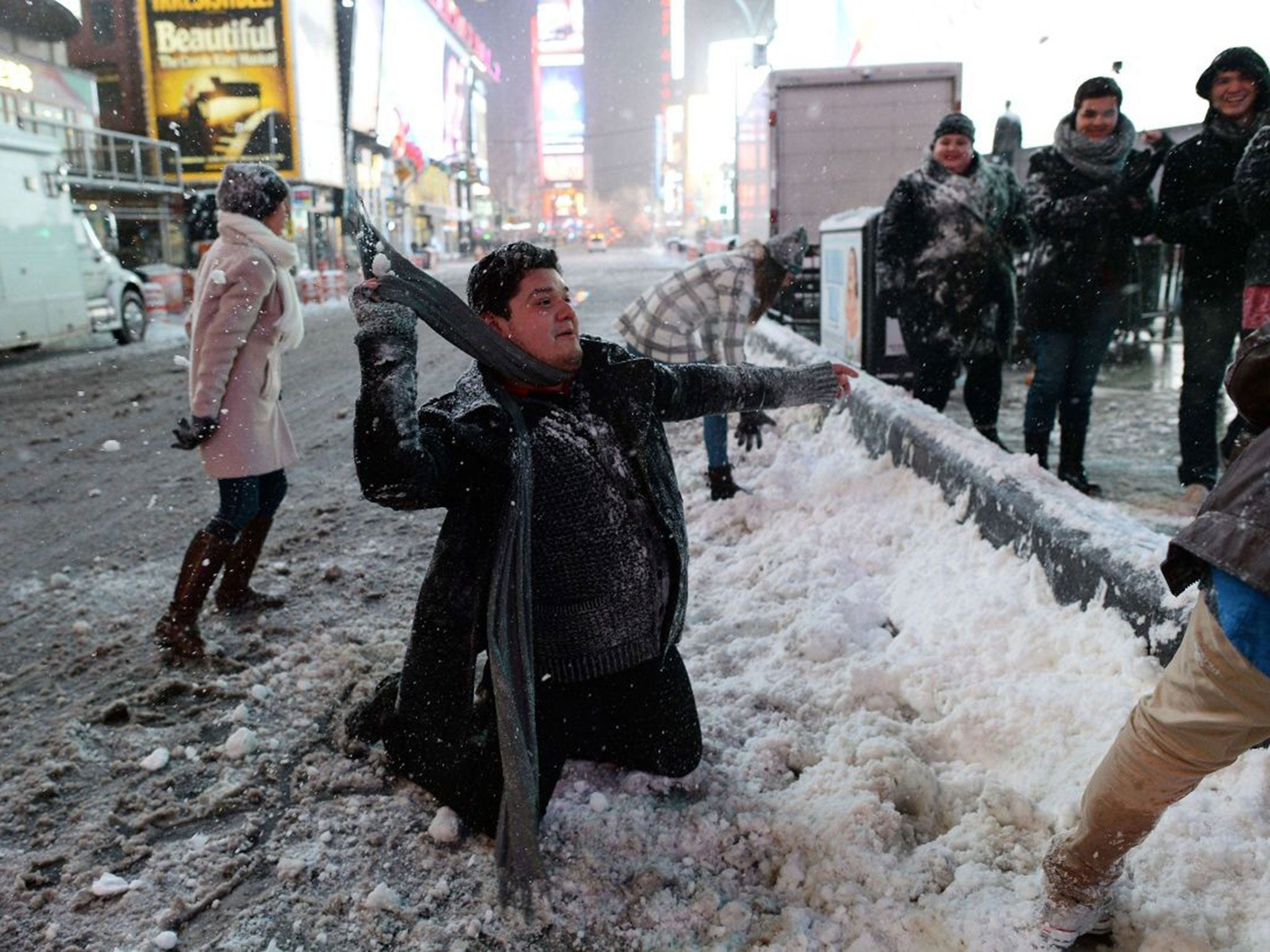 A group take a more light-hearted approach to the blizzard on a deserted street in New York's Times Square