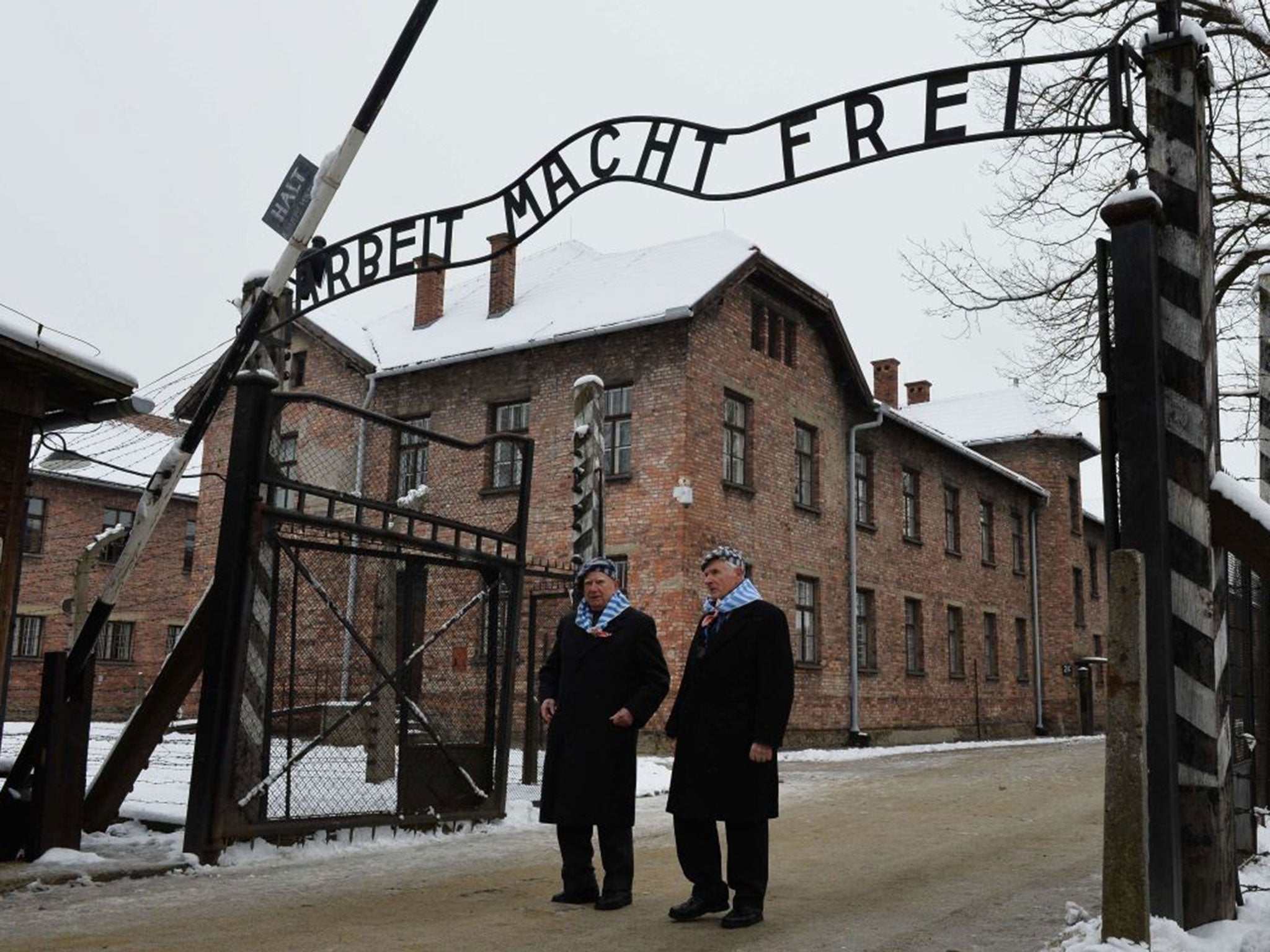 Auschwitz survivors walk through the gate of the former Auschwitz concentration camp as they arrive to attend commemorations for the 70th anniversary of the camp's liberation on 27January 2015