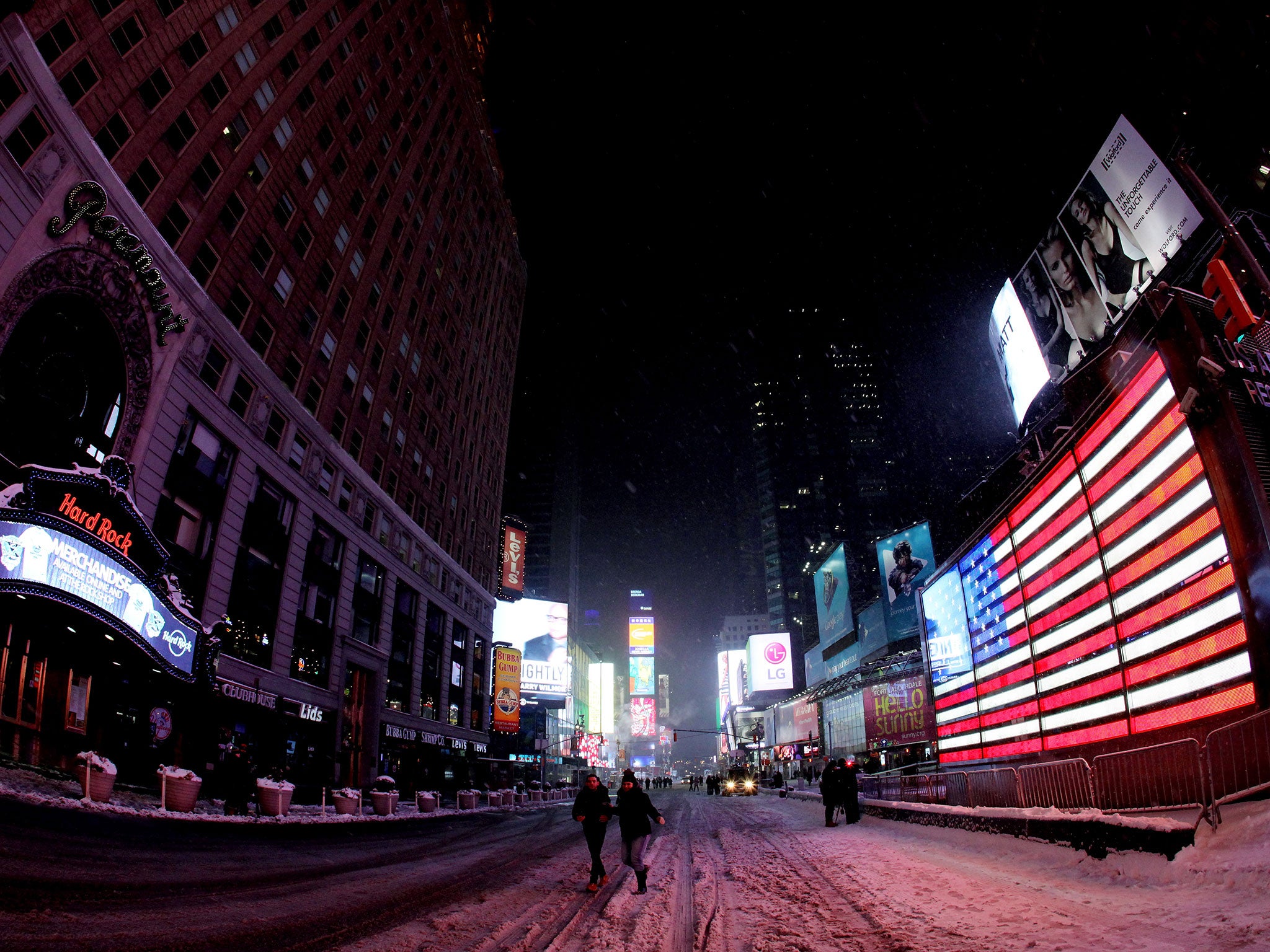 Pedestrians walk through a mostly empty Times Square