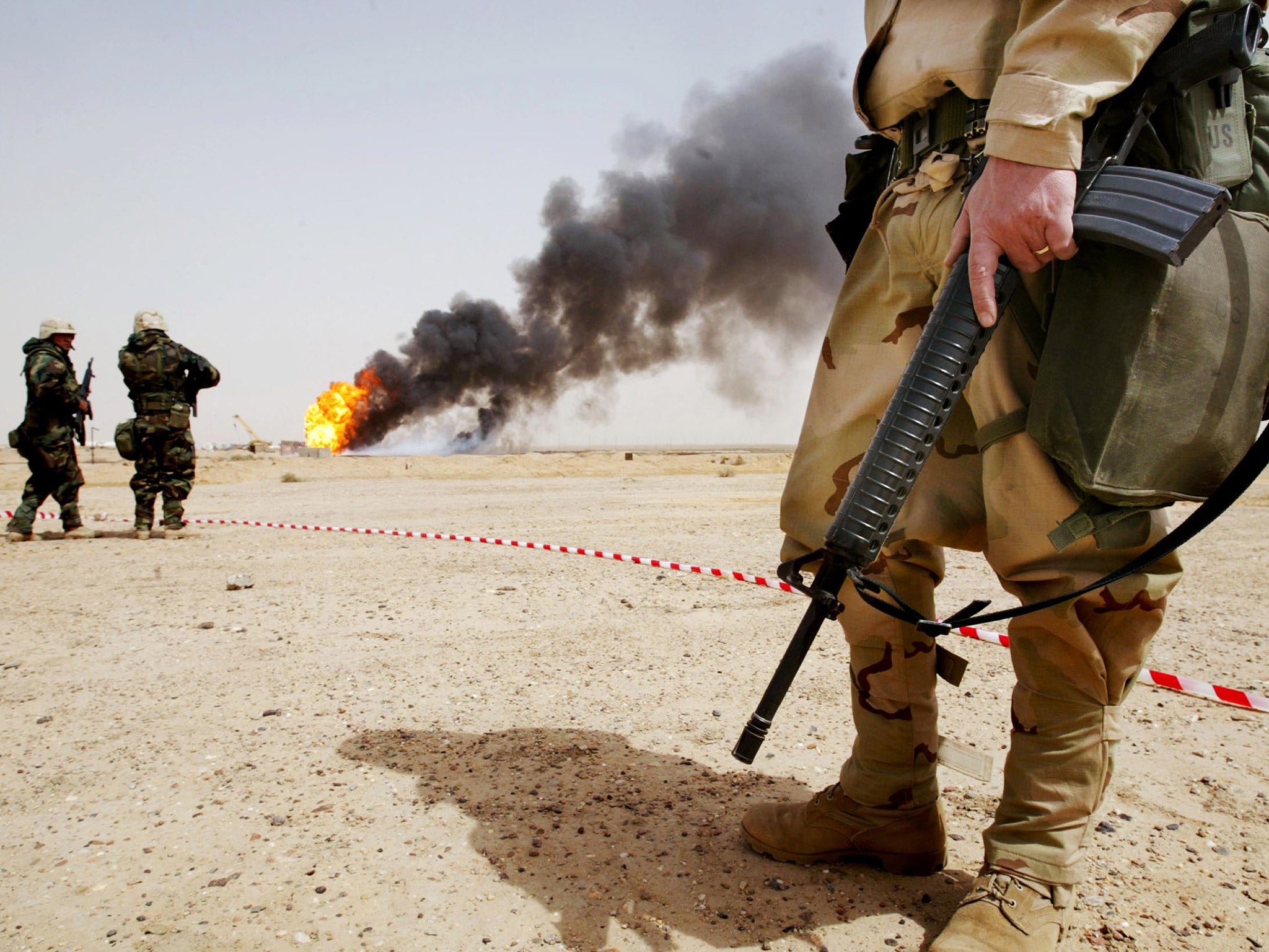 American troops stand near a burning oil well in Rumayla, Iraq, in 2003