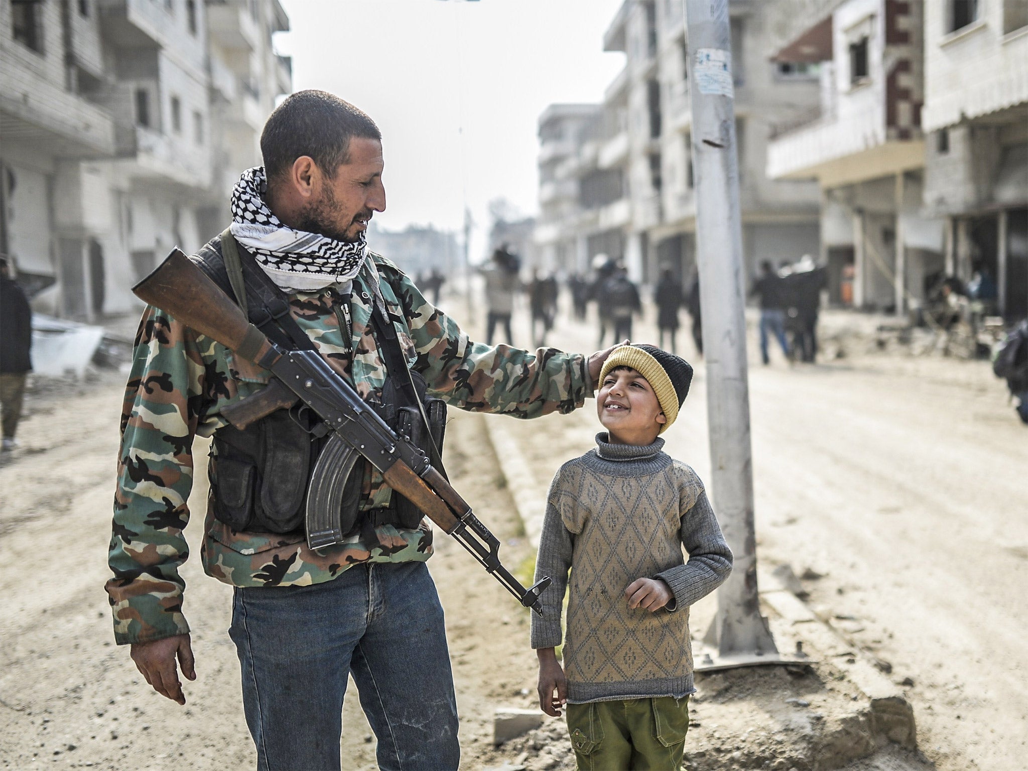 A Kurdish fighter walks with his child in Kobani after Isis was driven out of the strategic Syrian border town