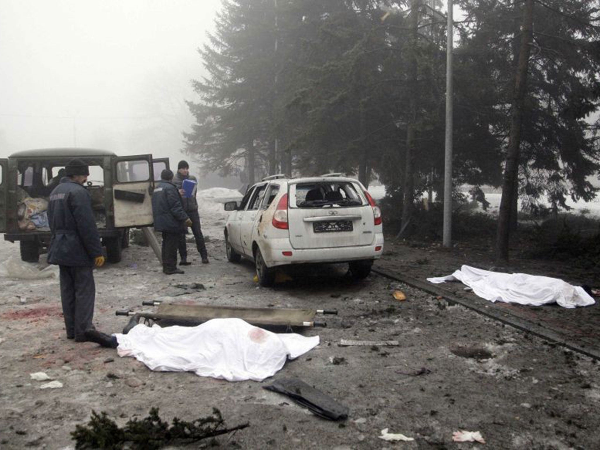 Men look at the covered bodies of victims at a site hit by shelling in Donetsk January 30, 2015