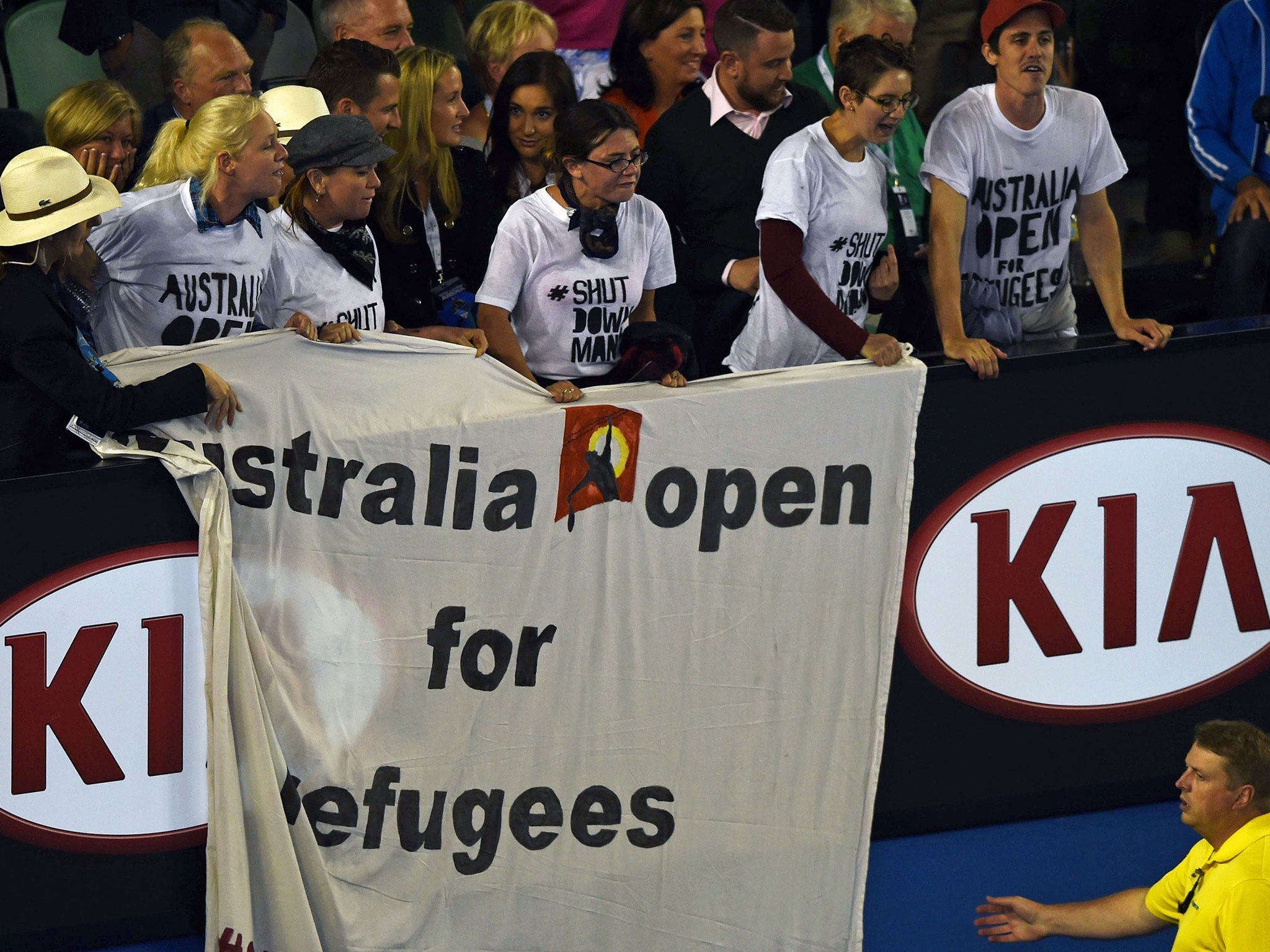 A member of security (bottom) prepares to pull down a banner displayed by protesters (wearing white shirts) in the stands