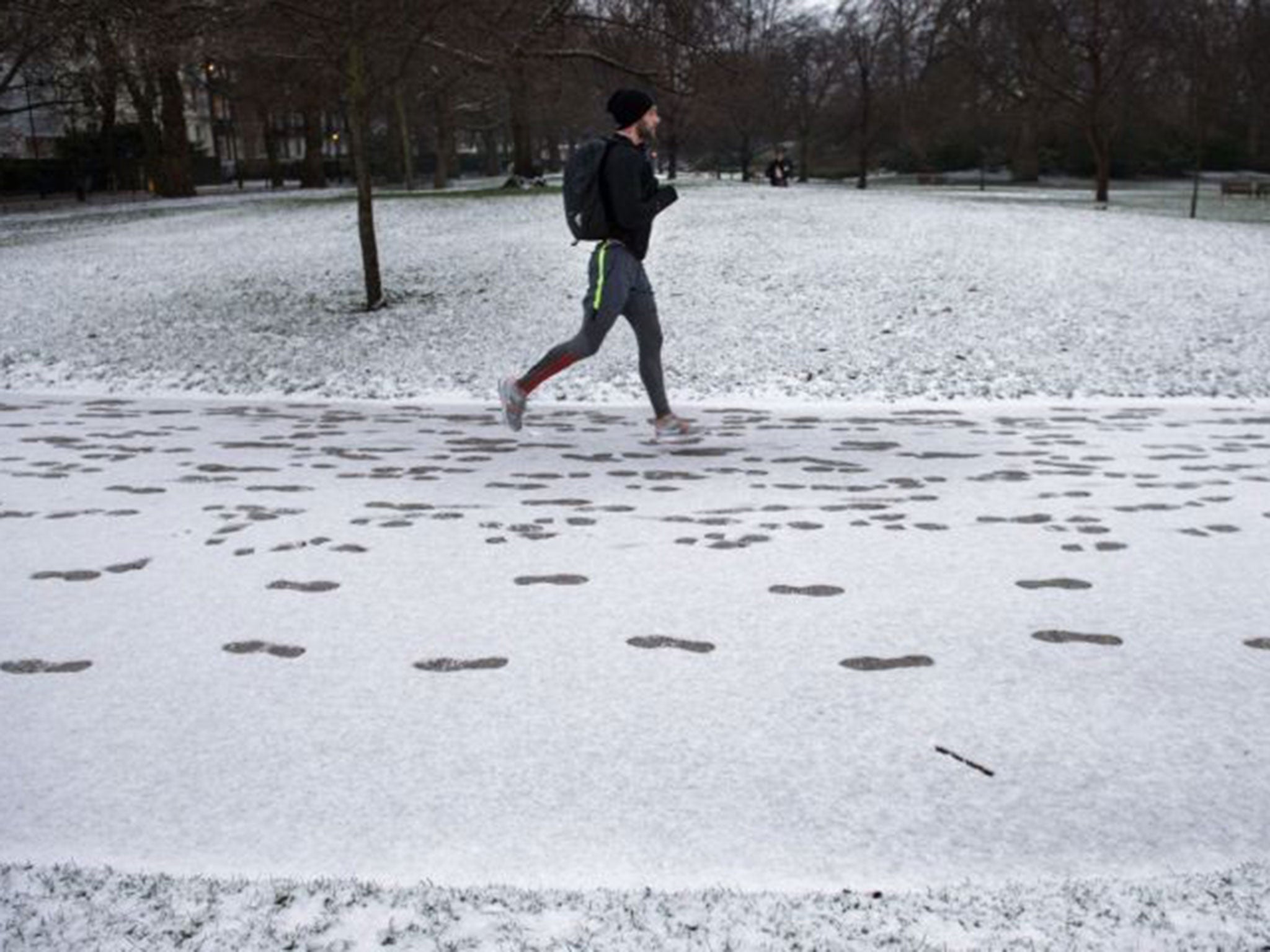 A man jogs through light snow in St James' Park, London, on 3 February