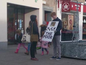 A student holds the "offensive" sign on Market Street in Fife