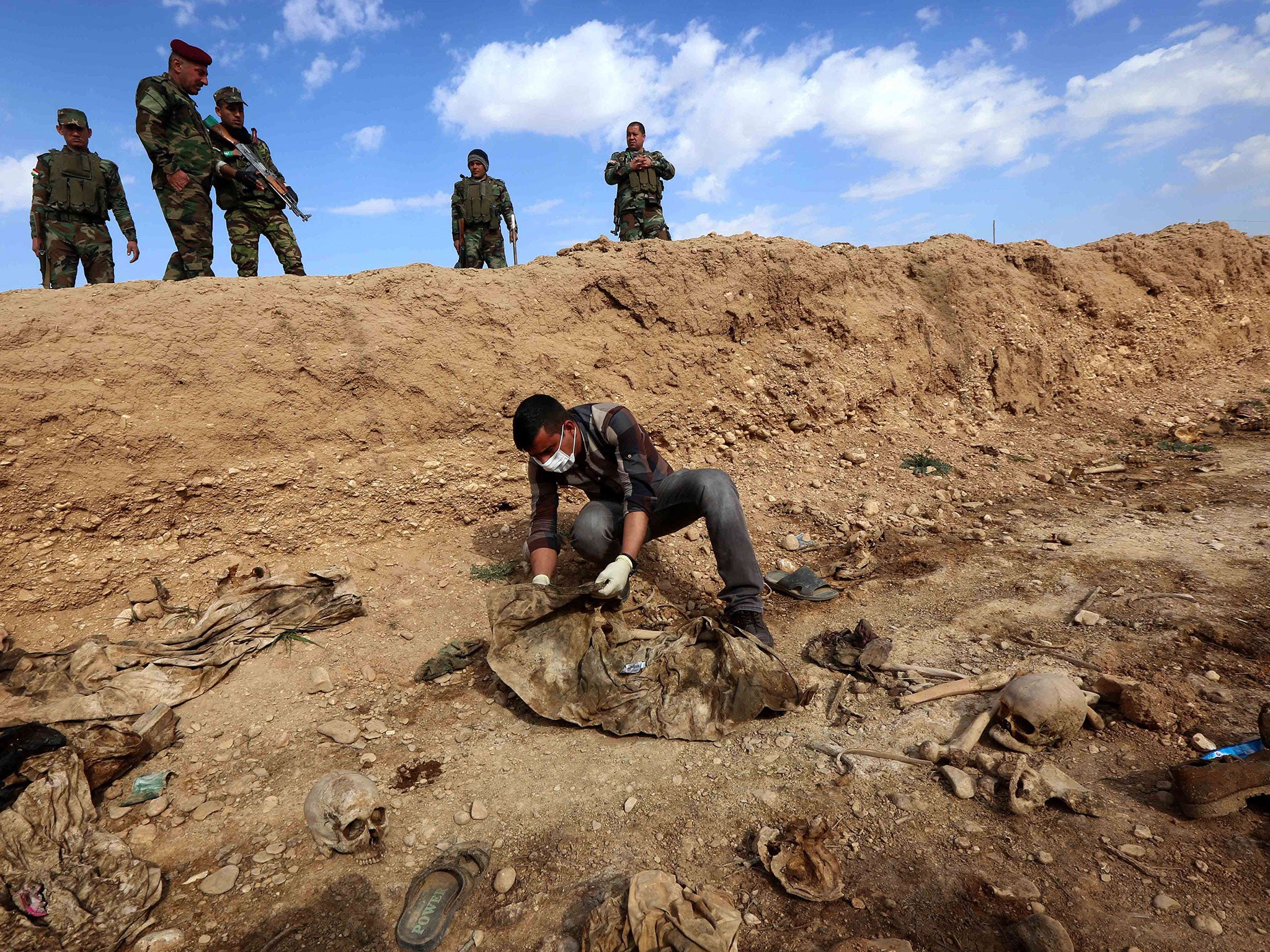 A man inspects the remains of members of the Yazidi minority killed by the Islamic State in the Sinjar area