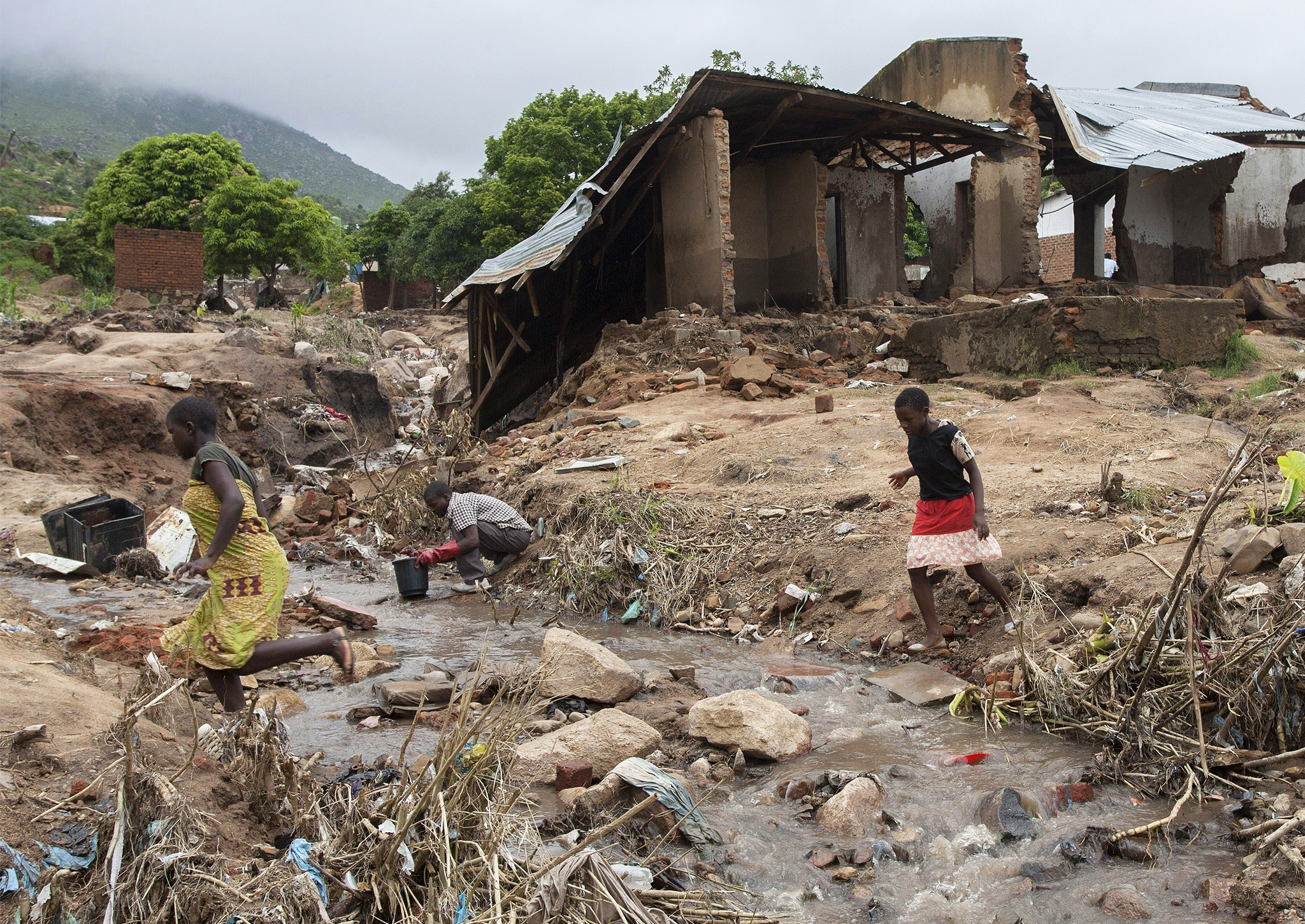 Girls cross a stream caused by flood waters at Chimwankhunda residential location in the suburb of Malawi's commercial city Blantyre