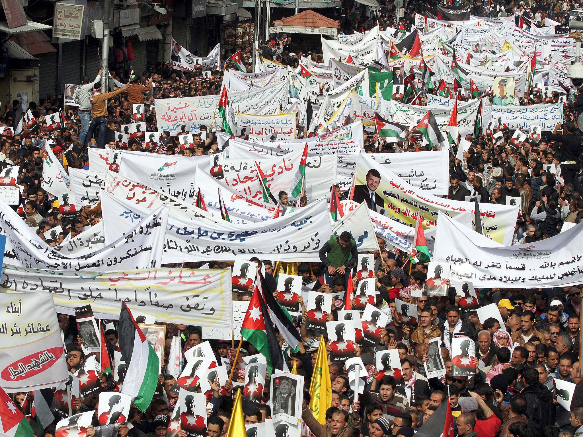 Jordanians carry banners and pictures of executed pilot Muath al-Kassasbeh in Amman while shouting slogans against Isis (EPA)