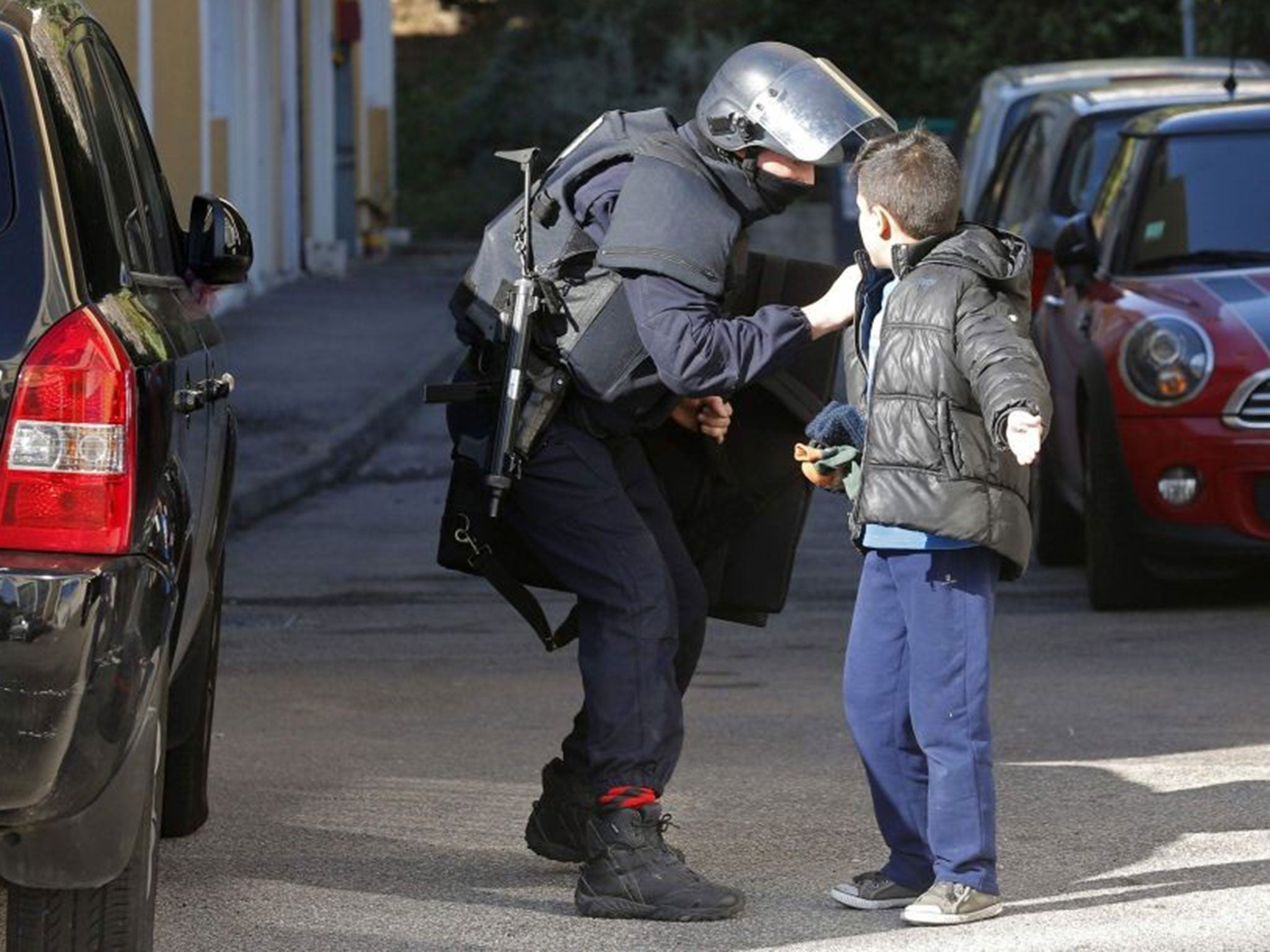 A French police officer speaks to a child outside a school as he secures the Castellane housing area in Marseille, February 9