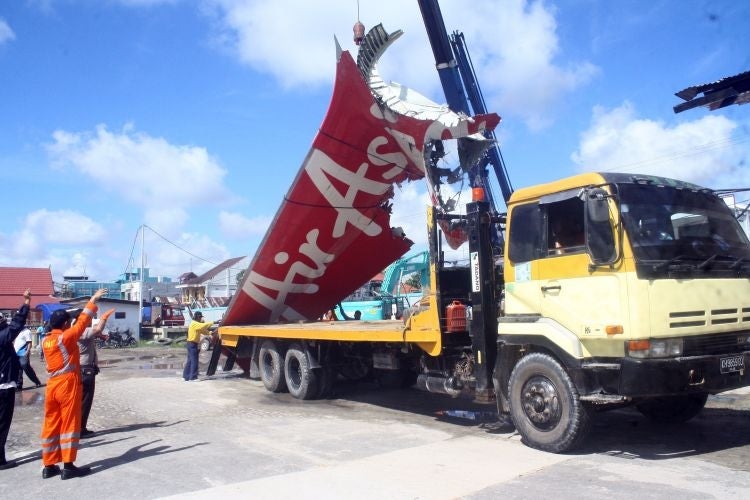 Workers load the tail of AirAsia flight QZ8501 onto a truck at Kumai sea port, in Central Kalimantan, on 7 February, before they transport it to Jakarta