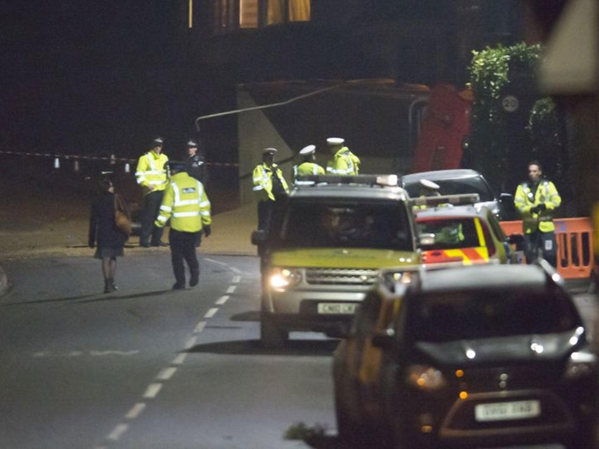 Police stand in front of a tipped over lorry after the tipper truck collided with vehicles and pedestrians on a hill in Lansdown Lane in Upper Weston in Bath