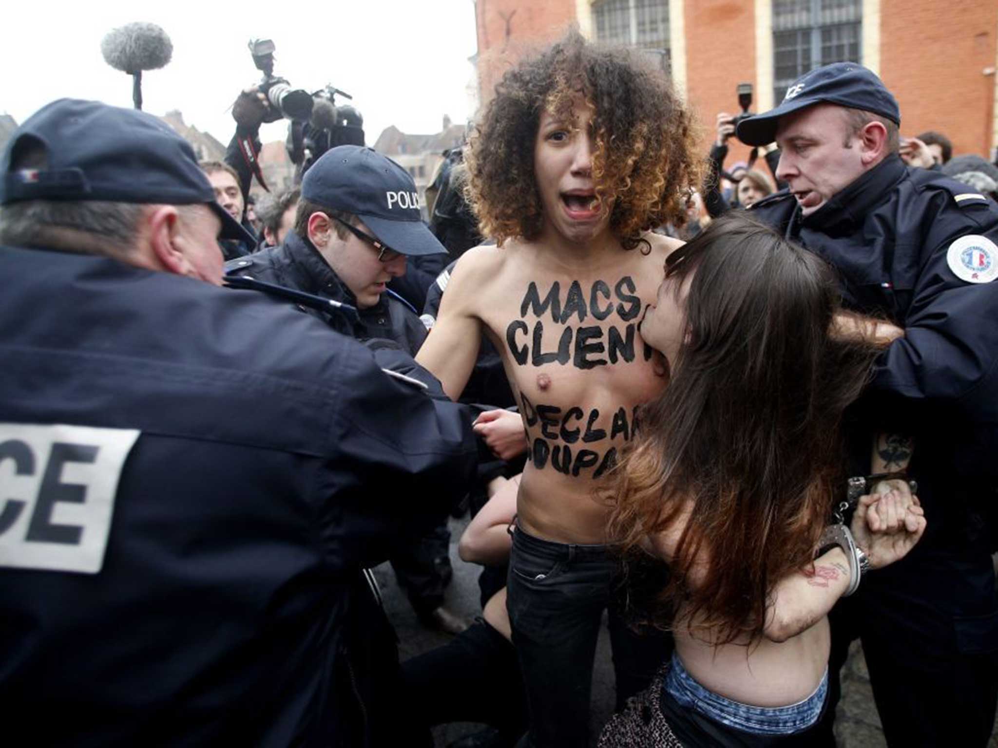 A femen protester with 'macs (French slang for the clients of prostitutes) are guilty' on her chest outside court