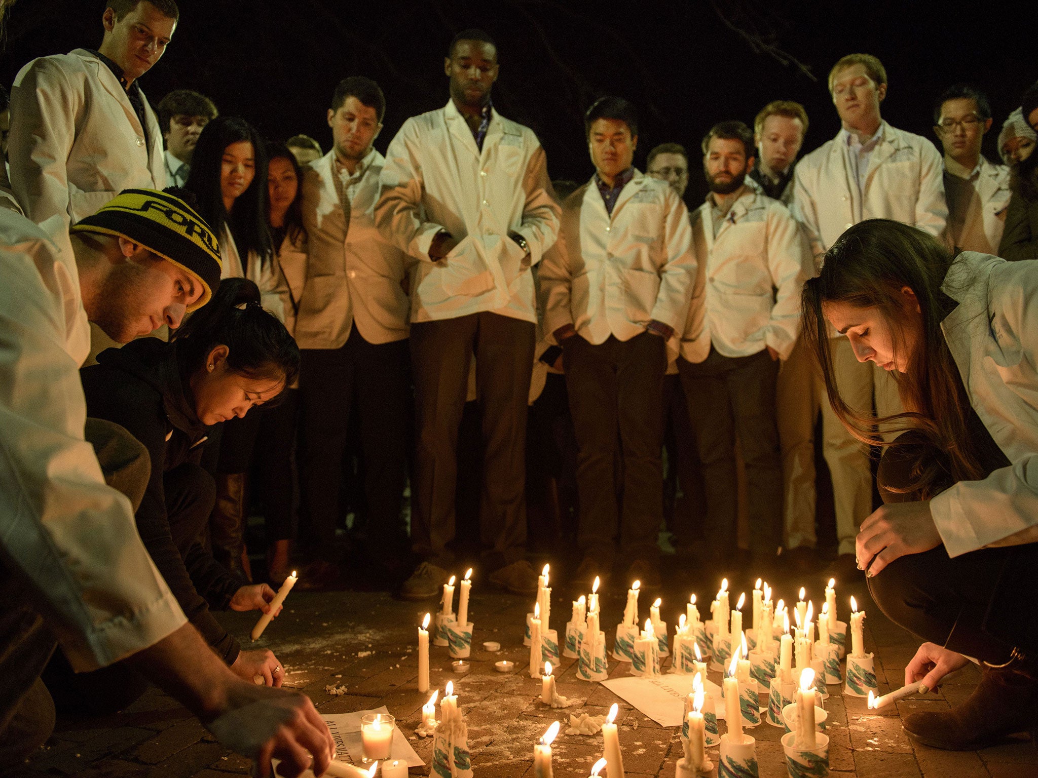 Dentistry students and others watch as a makeshift memorial is made during the vigil (Getty Images)