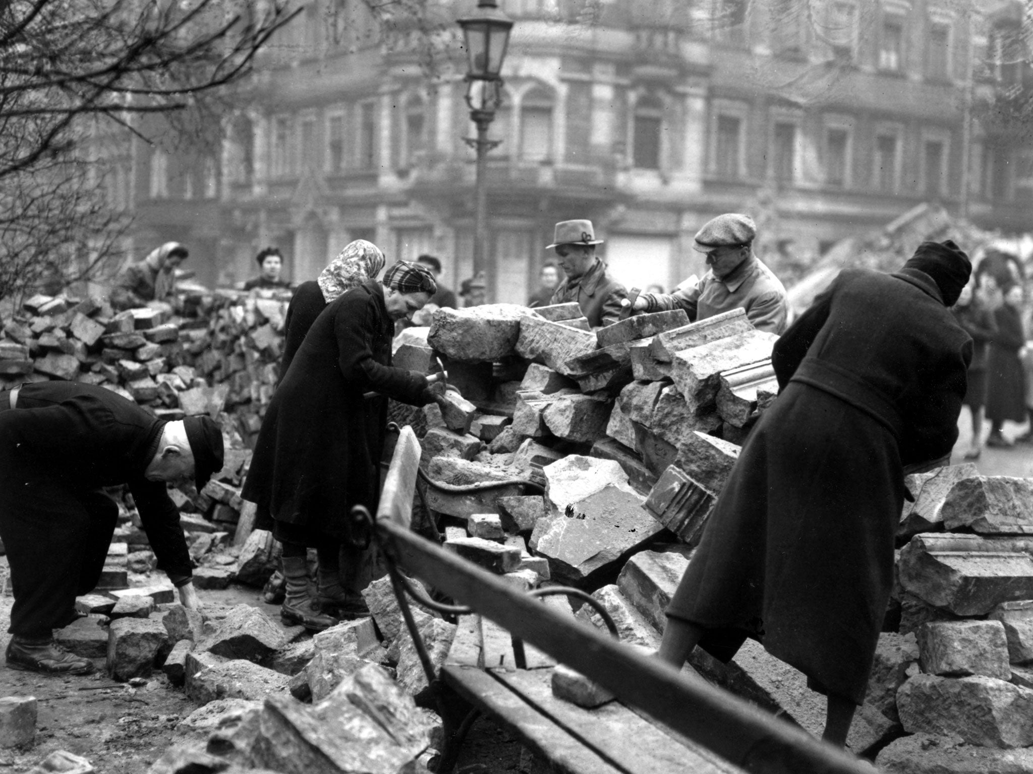 Volunteers help to clear the bomb damage debris (Getty)