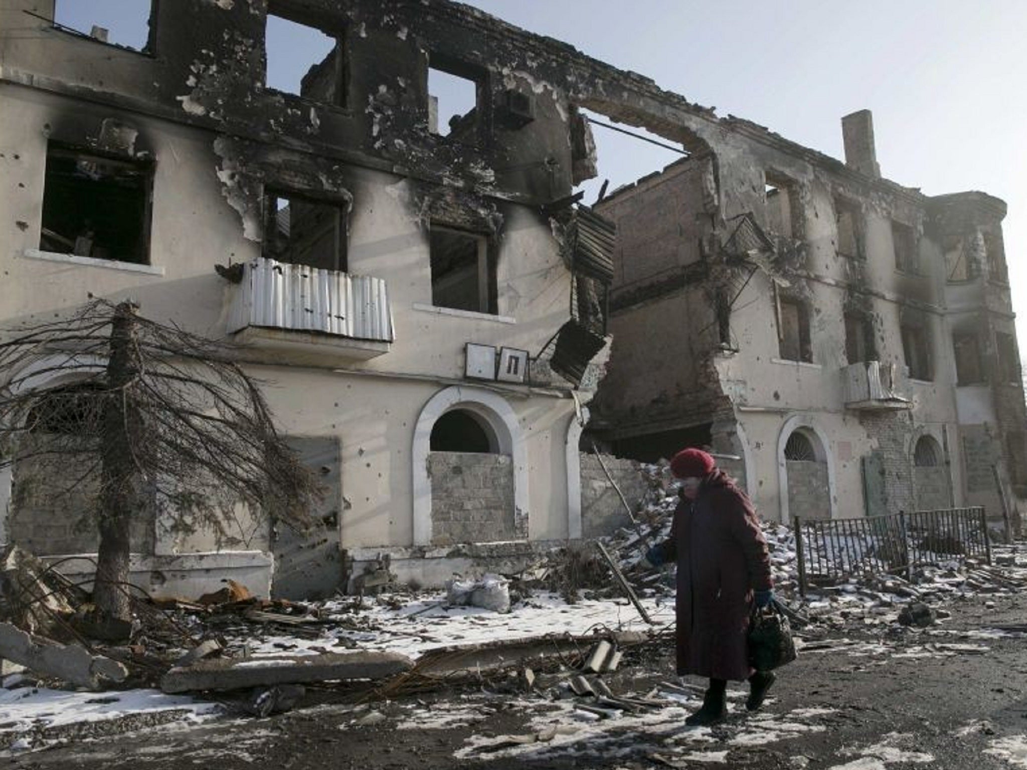 A woman walks past a damaged building in the town of Vuhlehirsk near Donetsk, Ukraine