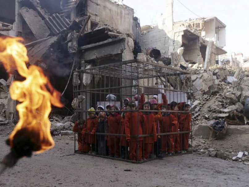 Children carry signs inside a cage during a protest against forces loyal to Syria's President Bashar al-Assad, in Douma on 15 February