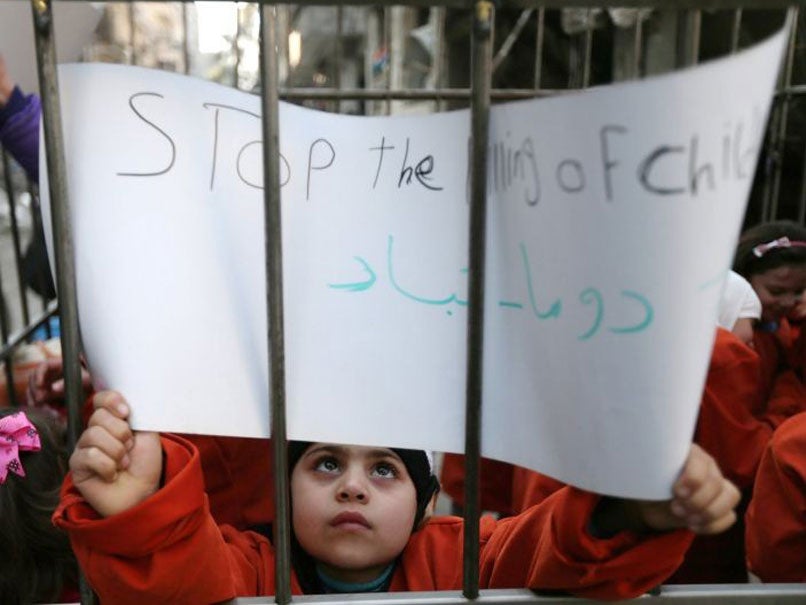 Children carry signs inside a cage during a protest against forces loyal to Syria's President Bashar al-Assad, in Douma on 15 February