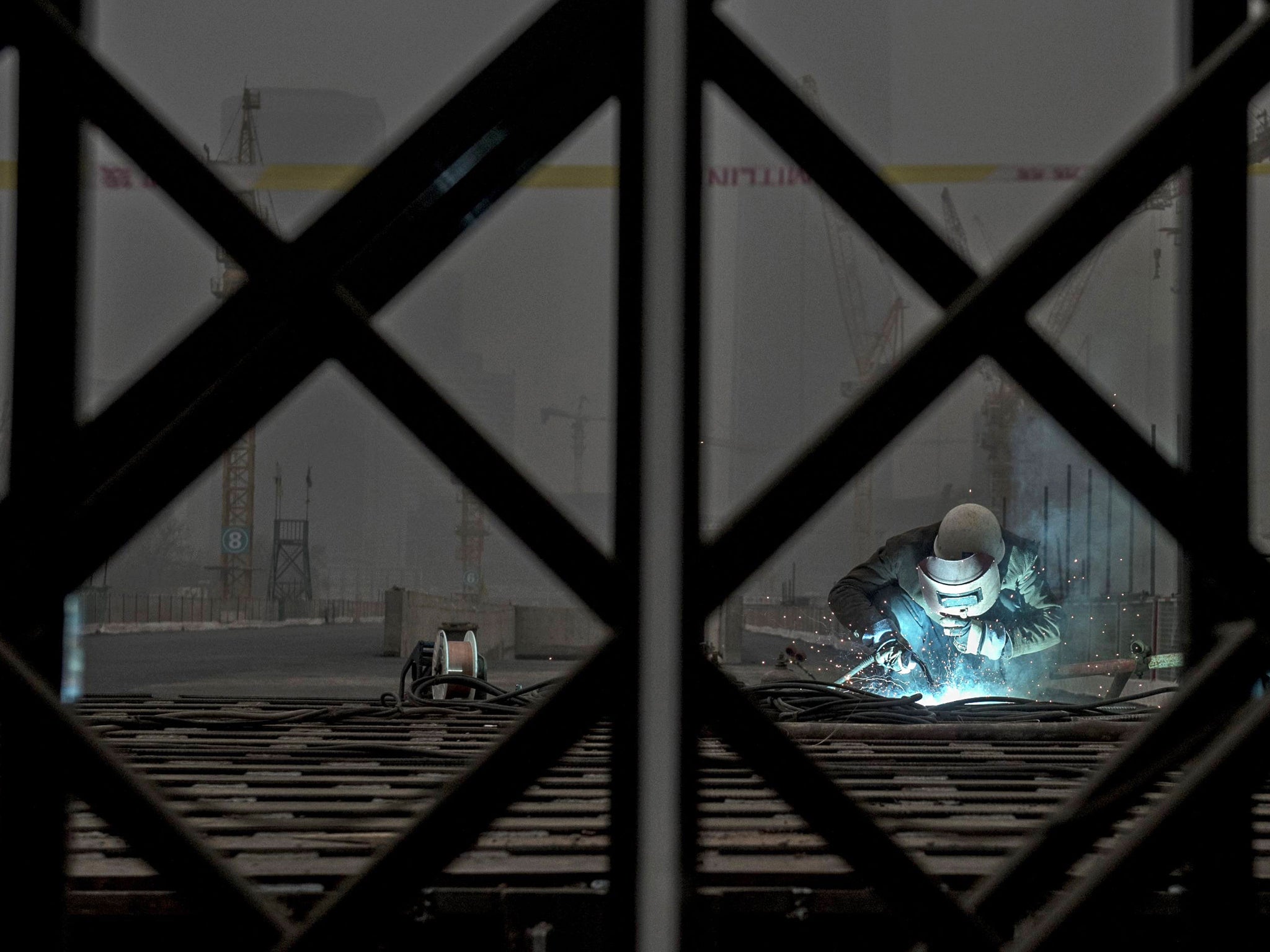 A Chinese worker welds at a construction site in heavy pollution on November 29, 2014 in Beijing, China