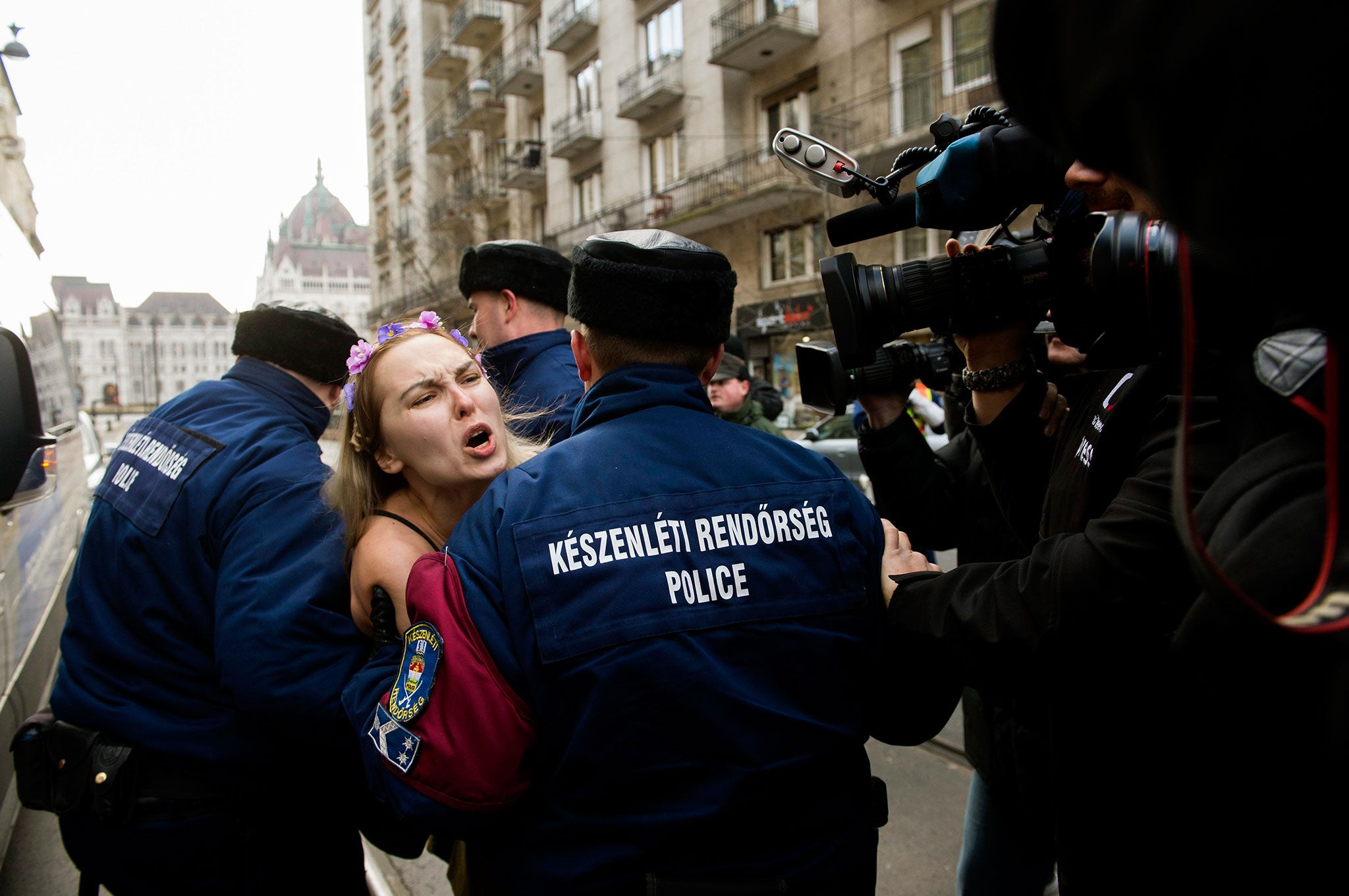 An activist of the feminist group Femen shouts as she is taken away by police officers during her protest against the visit of Russian President Vladimir Putin in Budapest