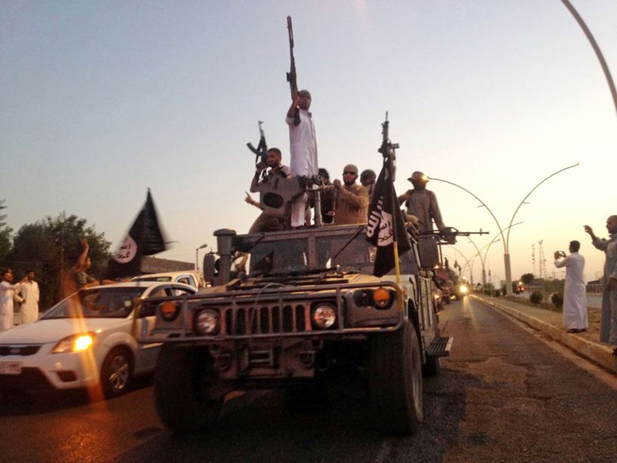 Fighters from the Islamic State group parade in a commandeered Iraqi security forces armored vehicle down a main road at the northern city of Mosul, Iraq.