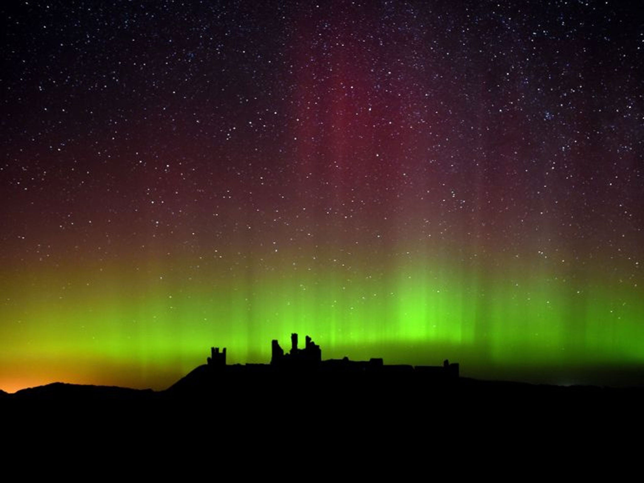 The aurora borealis over Dunstanburgh Castle (PA)