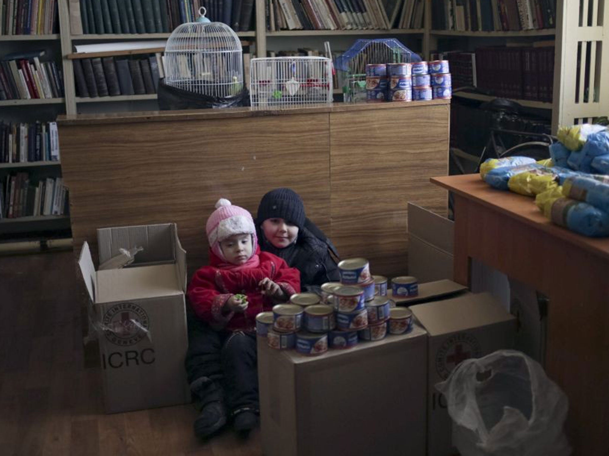 Children sit next to the humanitarian aid in the local Palace of Culture which is used as a bomb shelter in Mironovka village, near Debaltseve, on 17 February 2015.