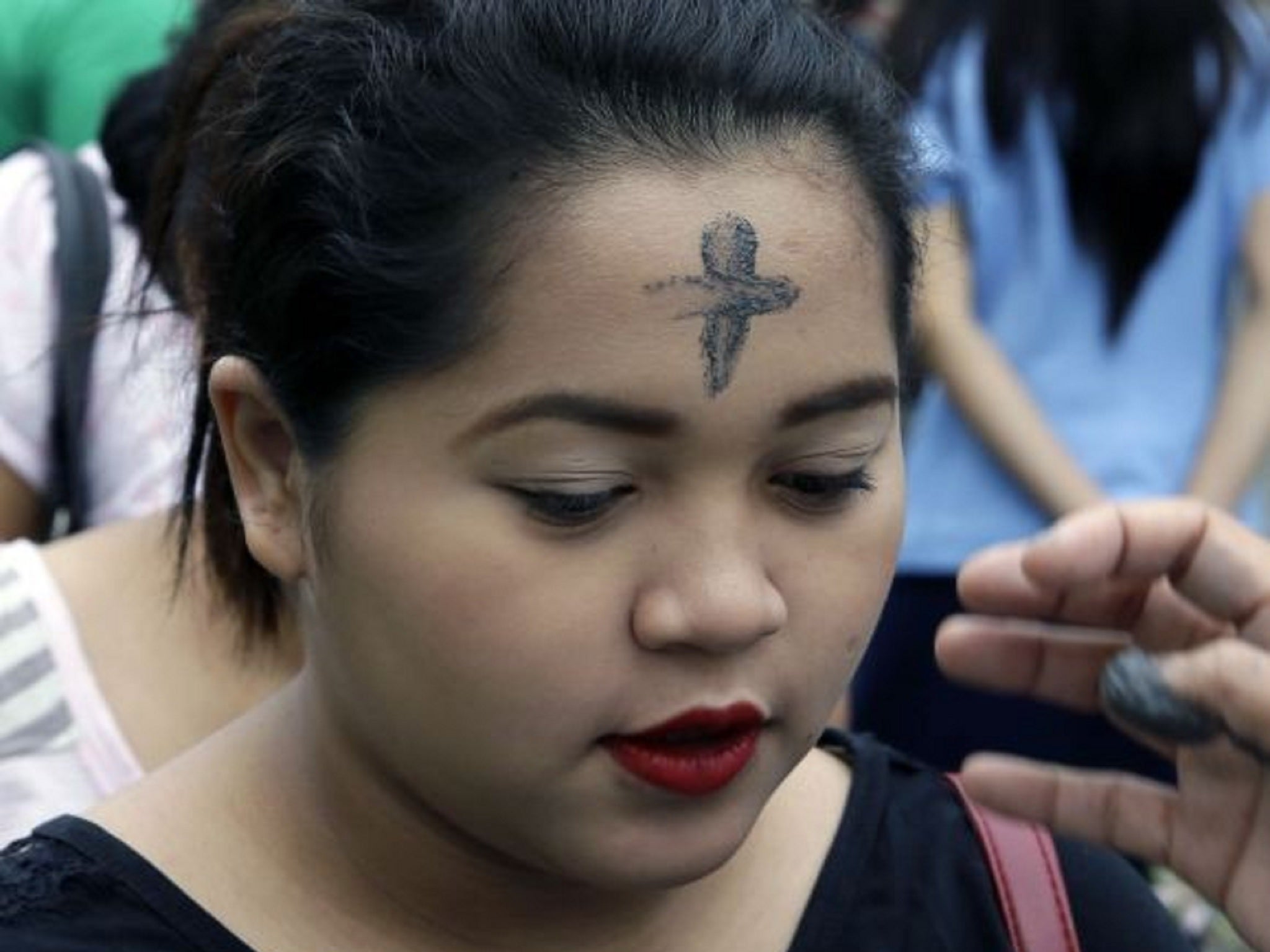 A woman has her head marked with a paste made from ashes on Ash Wednesday in the Philippines