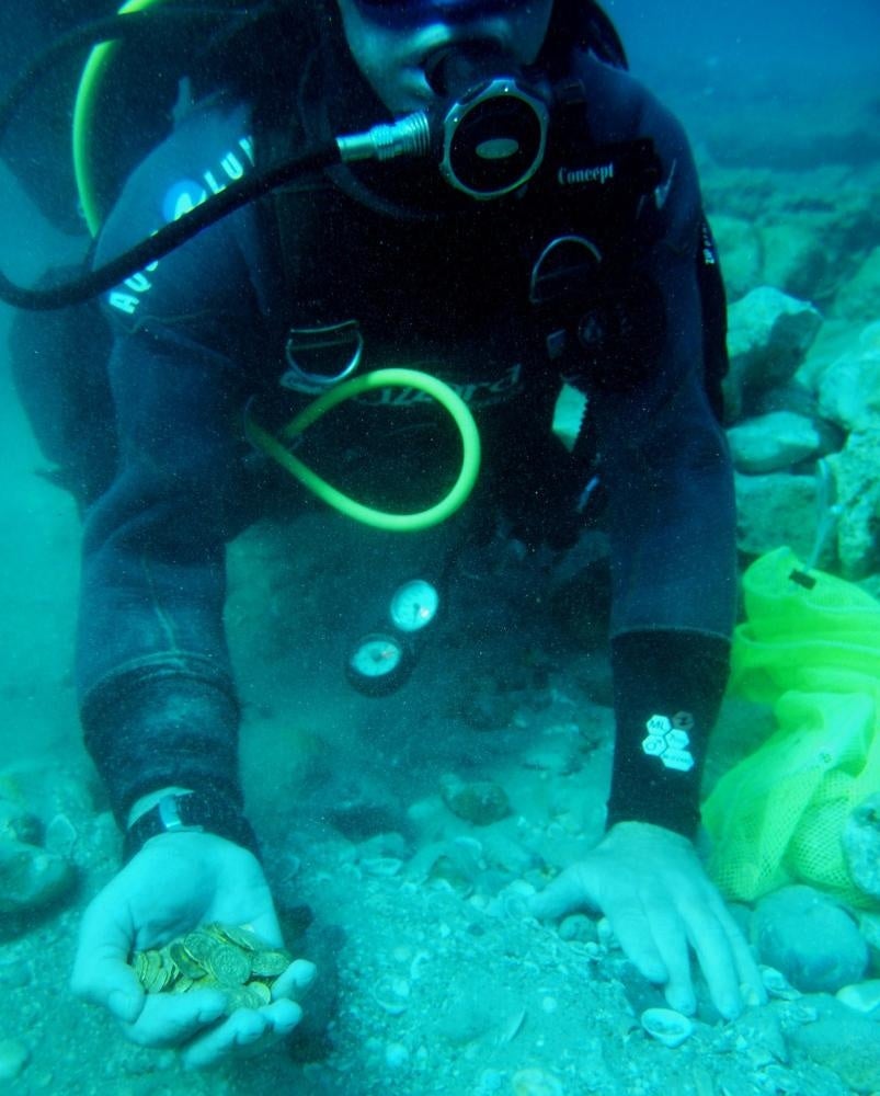 Diver holds the gold coins (Kobi Sharvit/AFP/Getty Images)