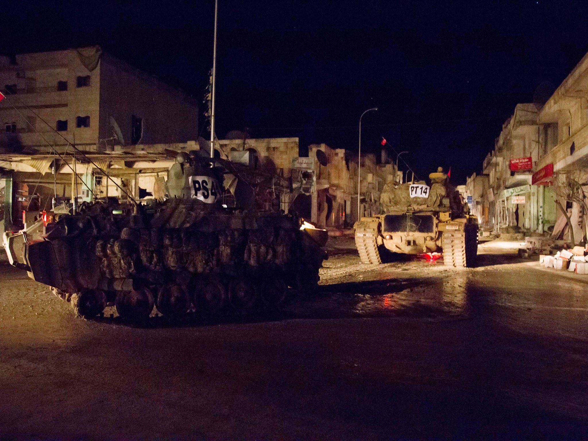 Turkish army vehicles drive in a street of the Syrian town of Kobani during an operation to relieve the garrison guarding the Suleyman Shah mausoleum in northern Syria