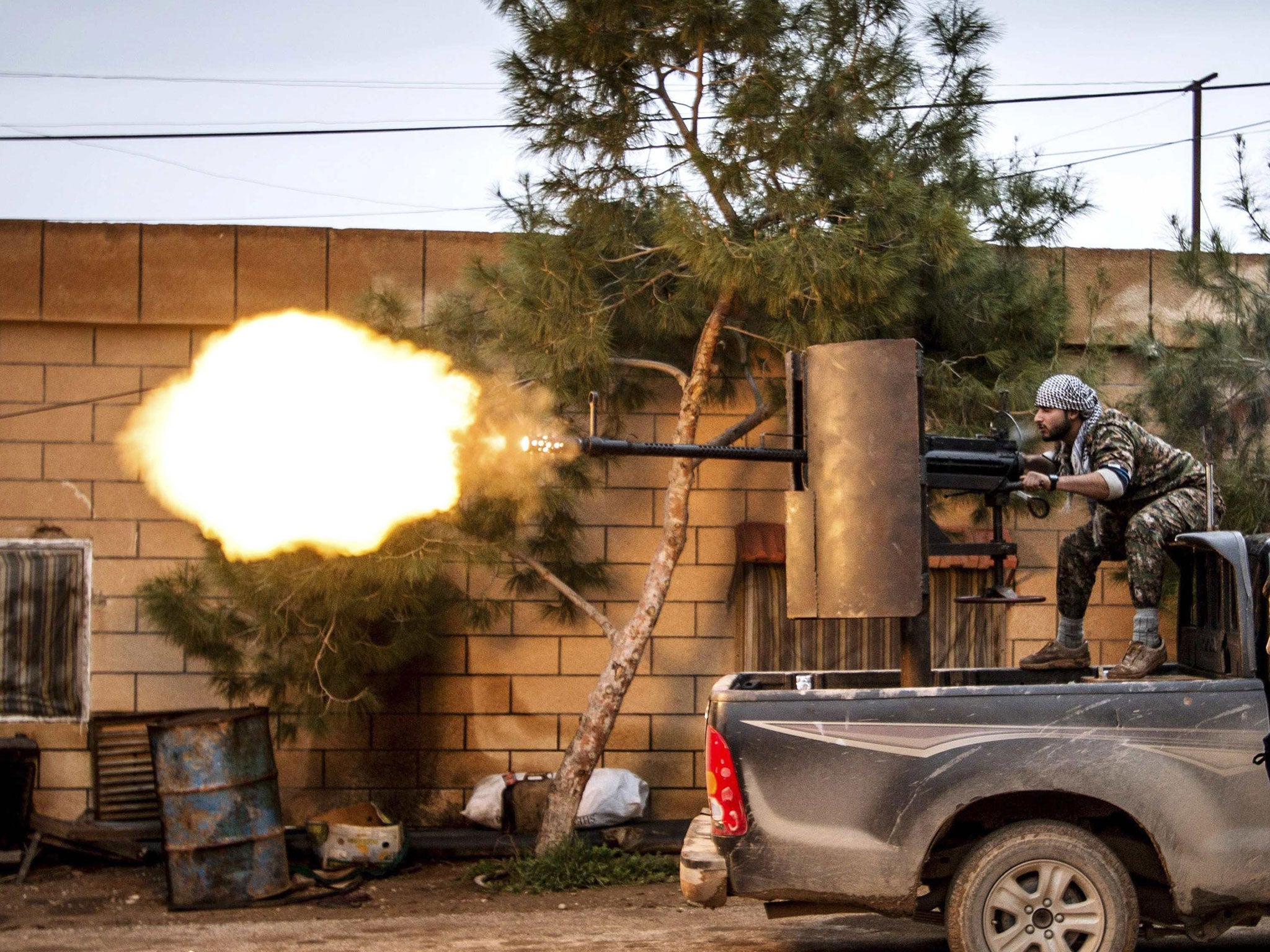 A fighter of the Kurdish People's Protection Units (YPG) fires an anti-aircraft weapon from Tel Tawil village in the direction of Isis fighters positioned in the countryside of the town of Tel Tamr