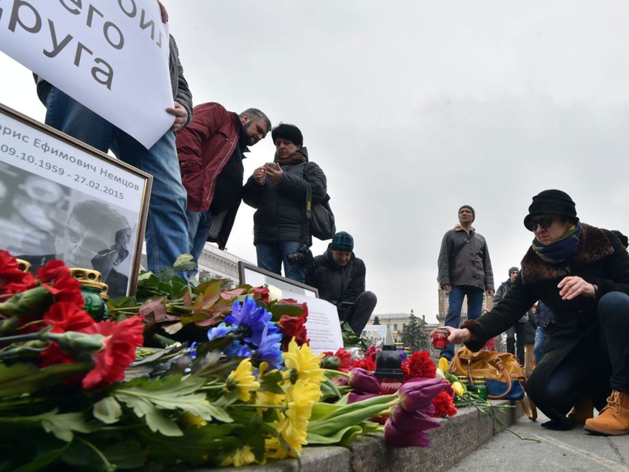 Mourners in Kiev's Independence Square hold a placard reading "'Putin killed my friend' during a memorial ceremony for Boris Nemtsov in Ukraine on 28 February